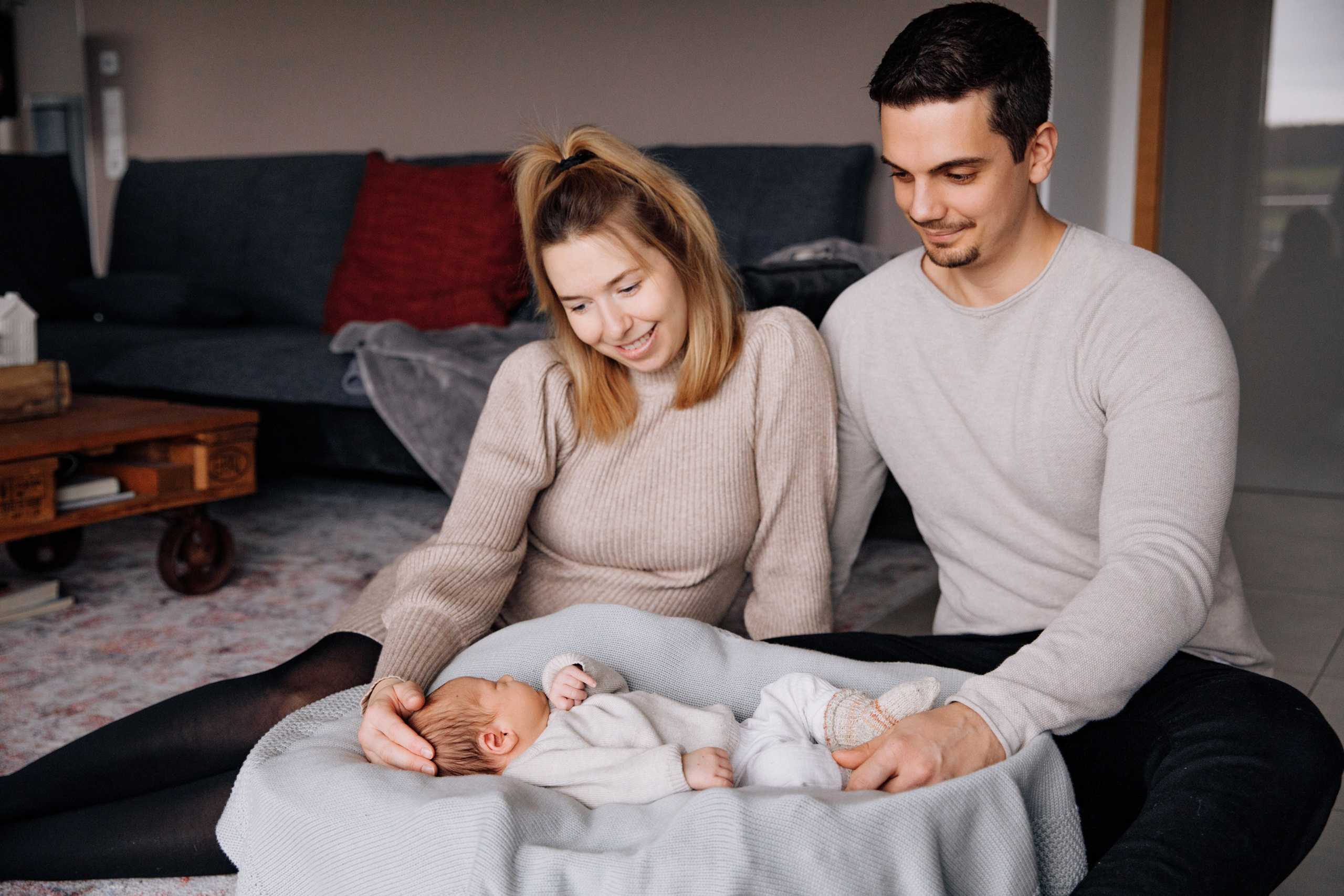 Eltern schauen liebevoll auf ihr schlafendes Neugeborenes.