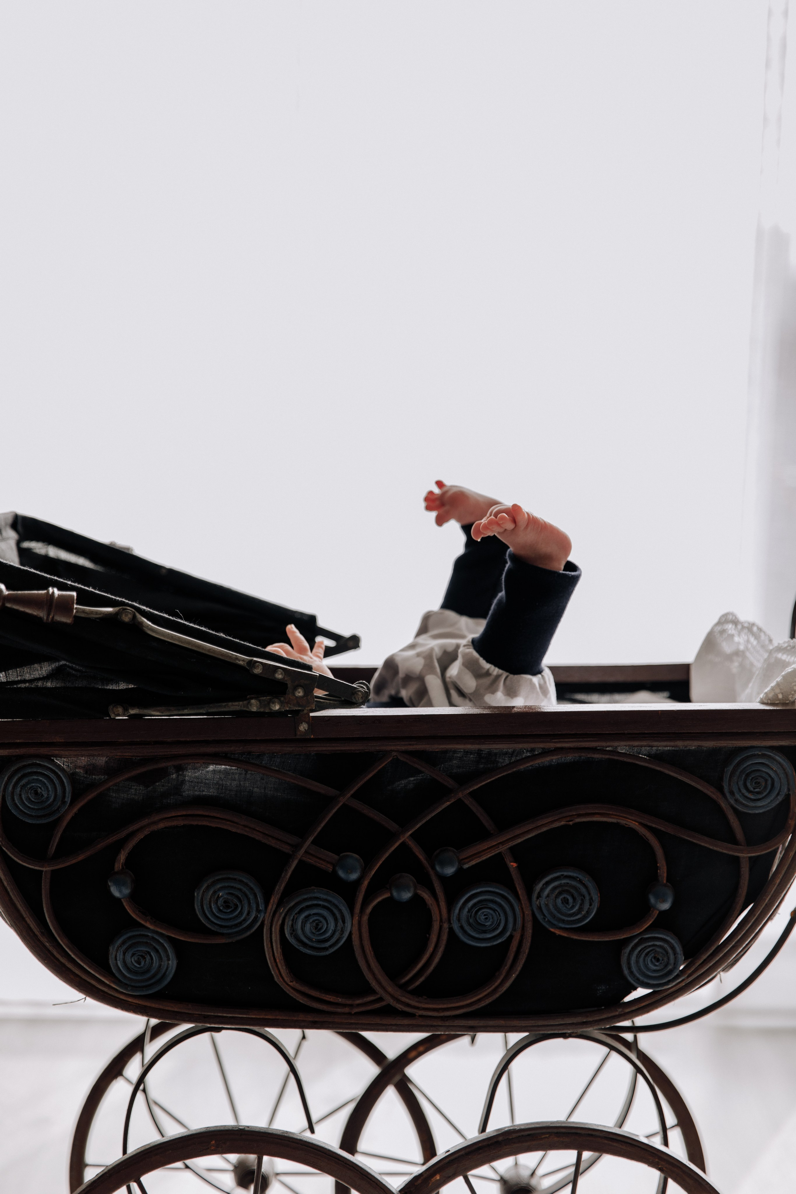 Babys Füße ragen aus einem antiken Puppenwagen hervor.