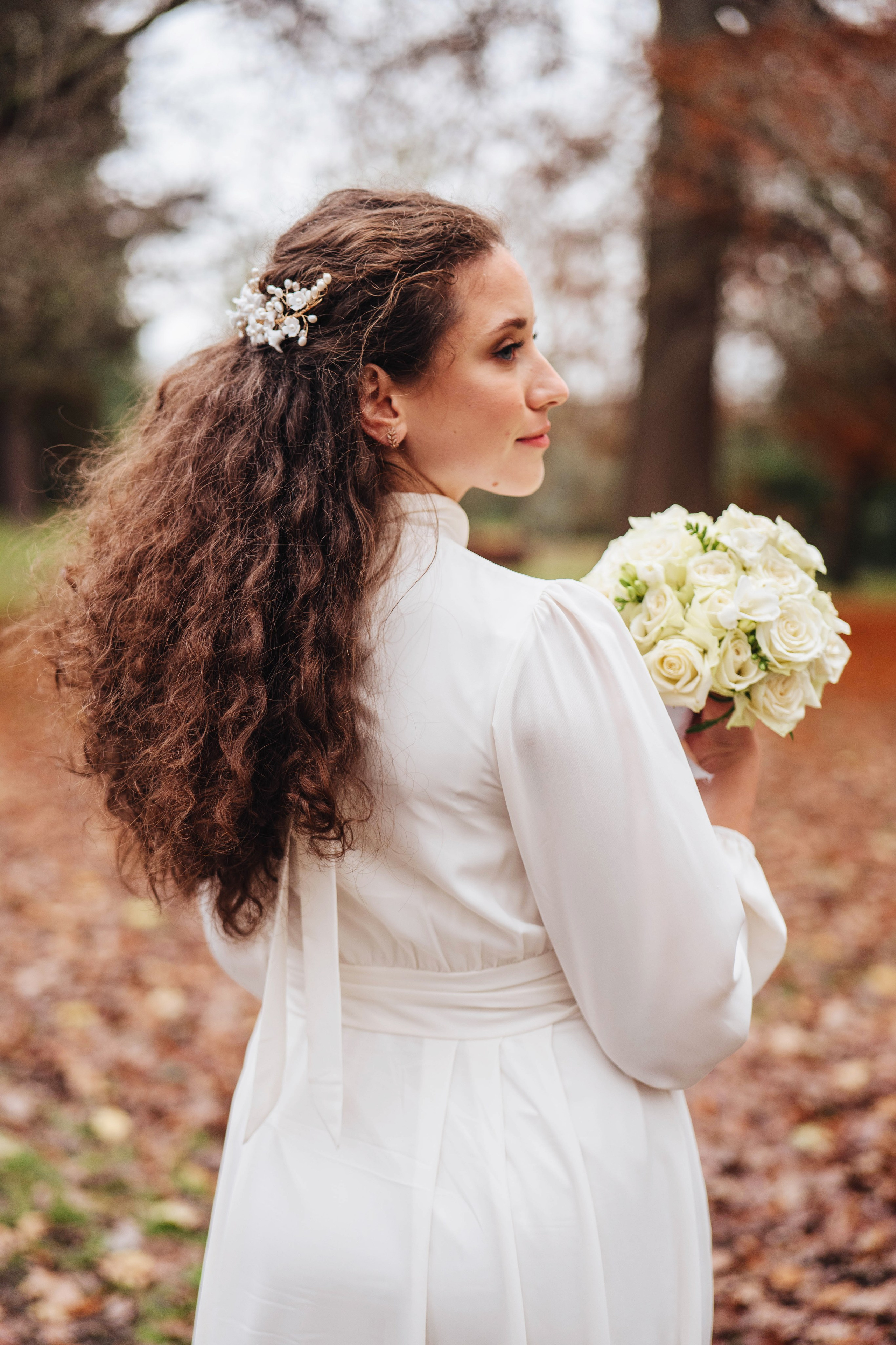 The bride walking along in an autumn park with a bouquet of flowers.
