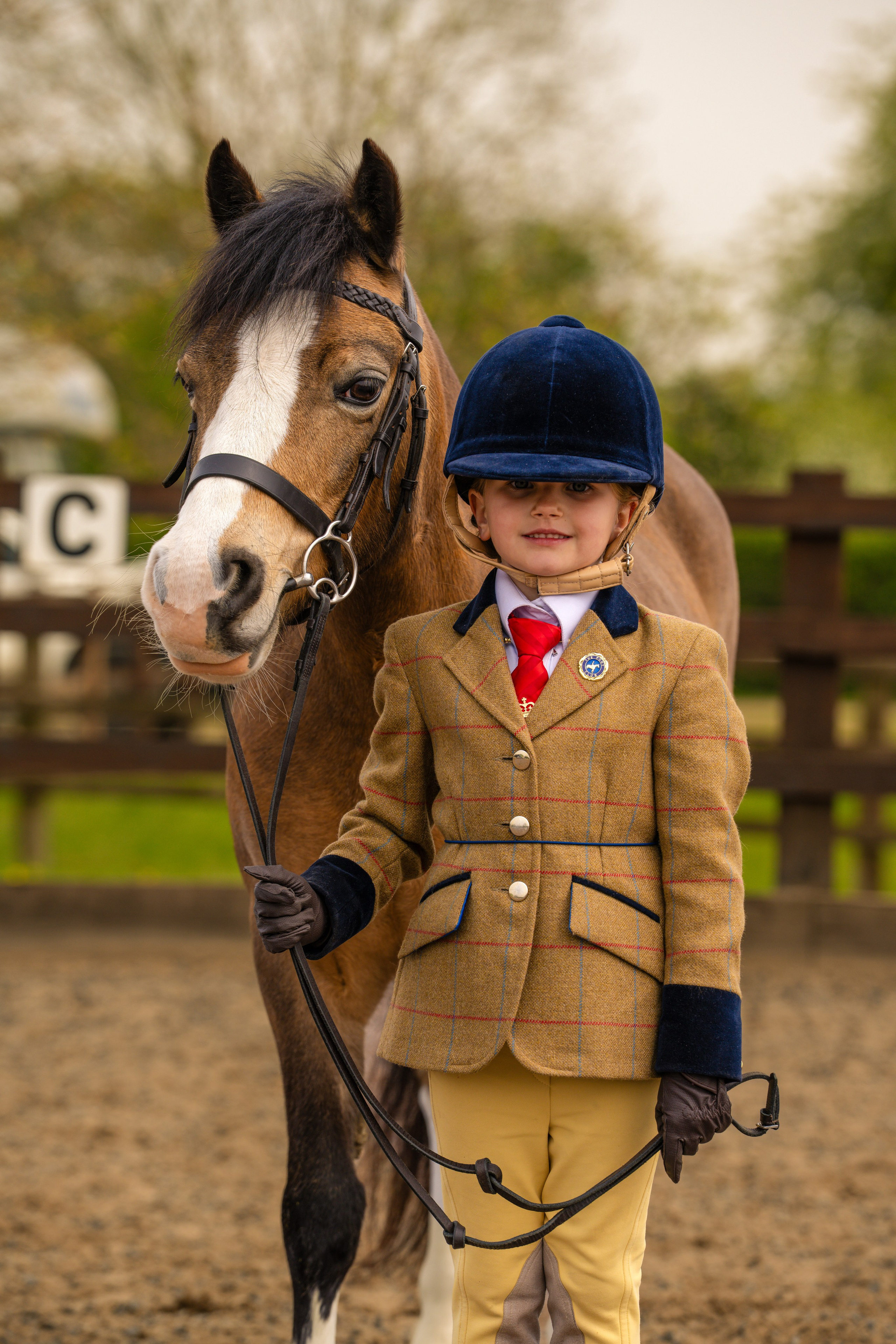 Confident young equestrian posing with horse in formal gear