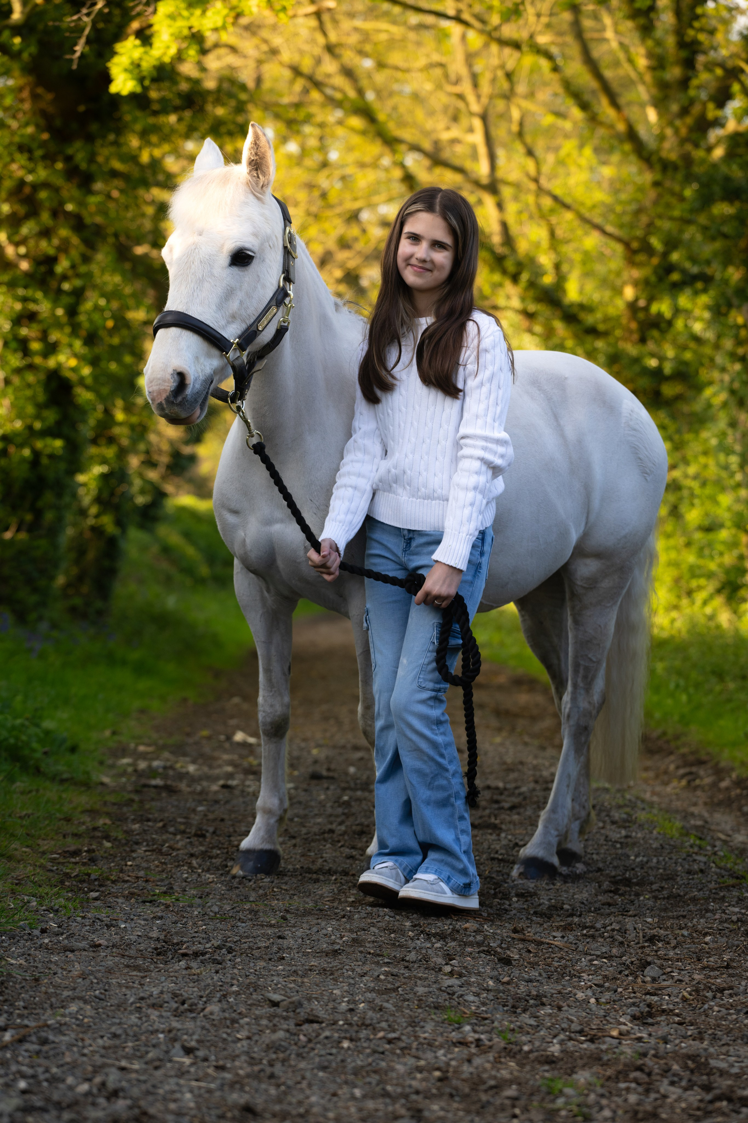Happy girl holding reins of her pony during golden light portrait session