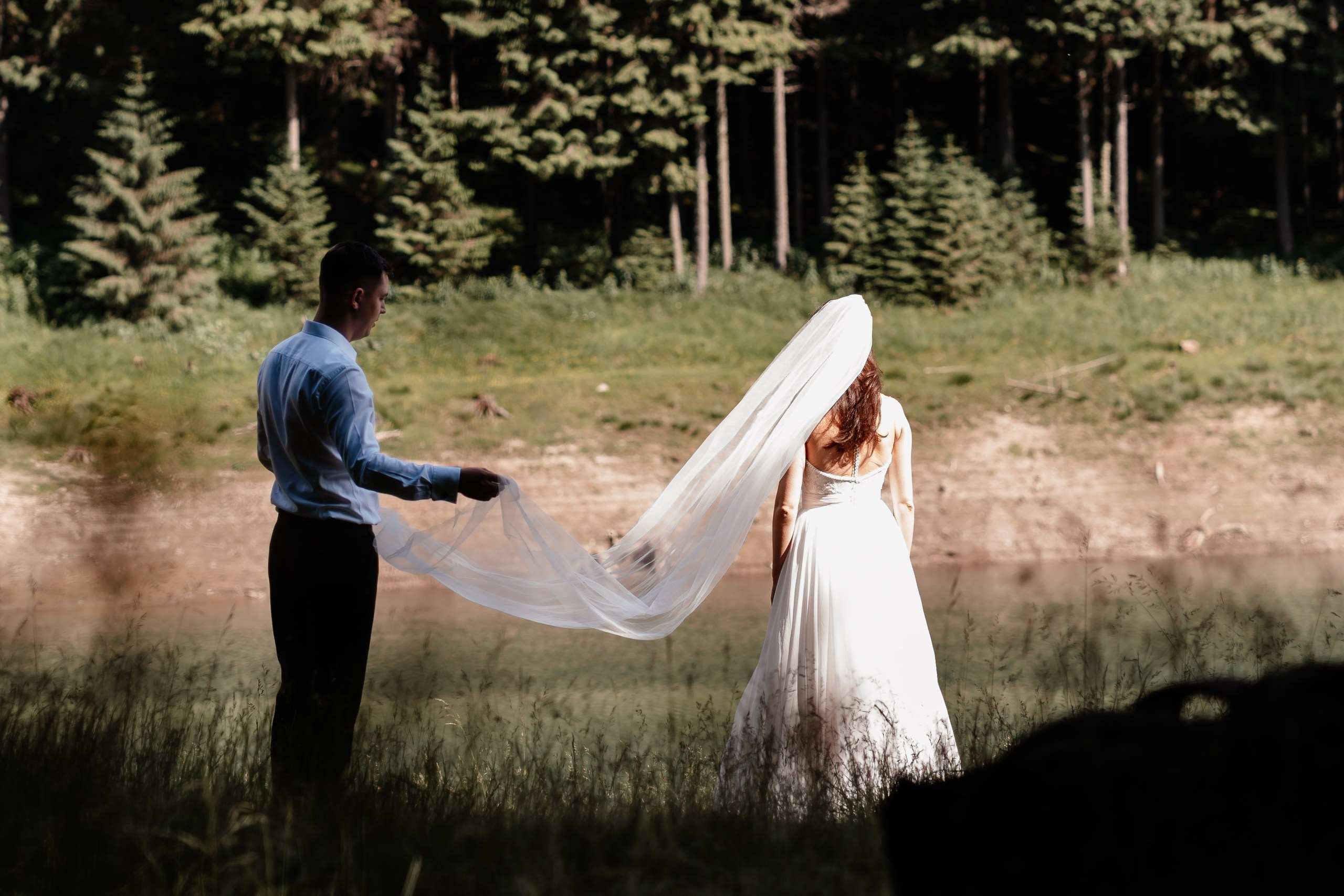 Moment emoționant între miri în ziua nunții, surprins într-un cadru natural și romantic, la Lacul Bolboci. Fotografie de nuntă profesională, editată artistic pentru a evidenția emoția și eleganța evenimentului.