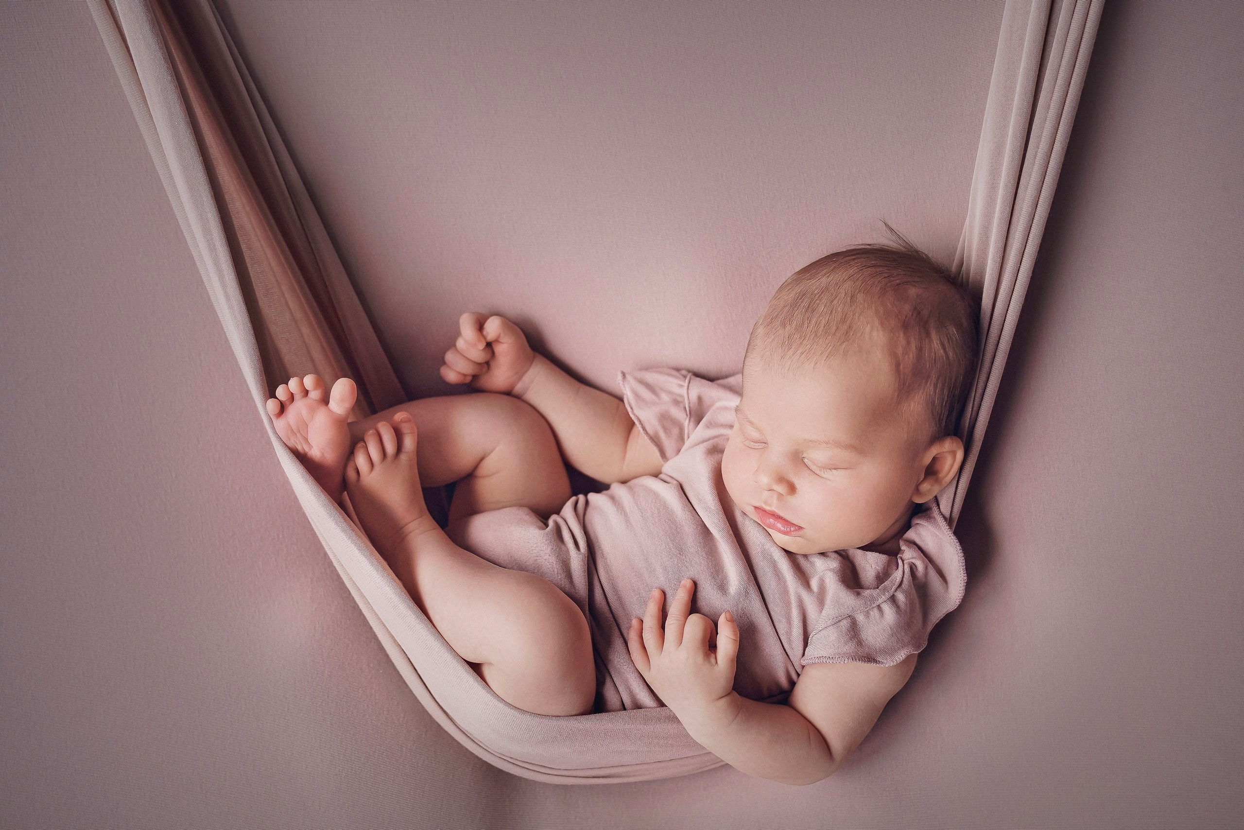 Newborn baby sleeping peacefully in a fabric swing