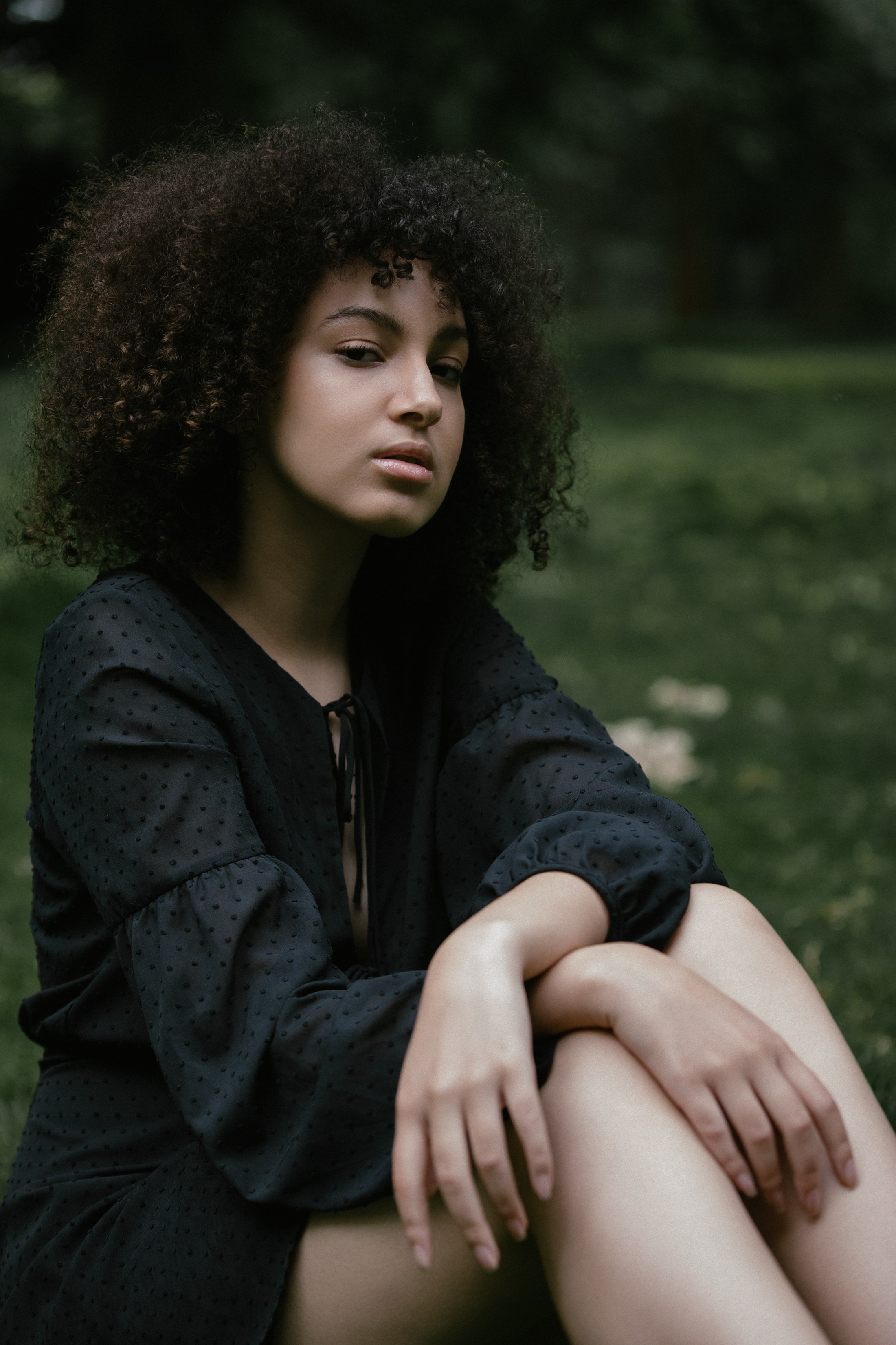 Outdoor portrait, woman sitting in grass with confident gaze