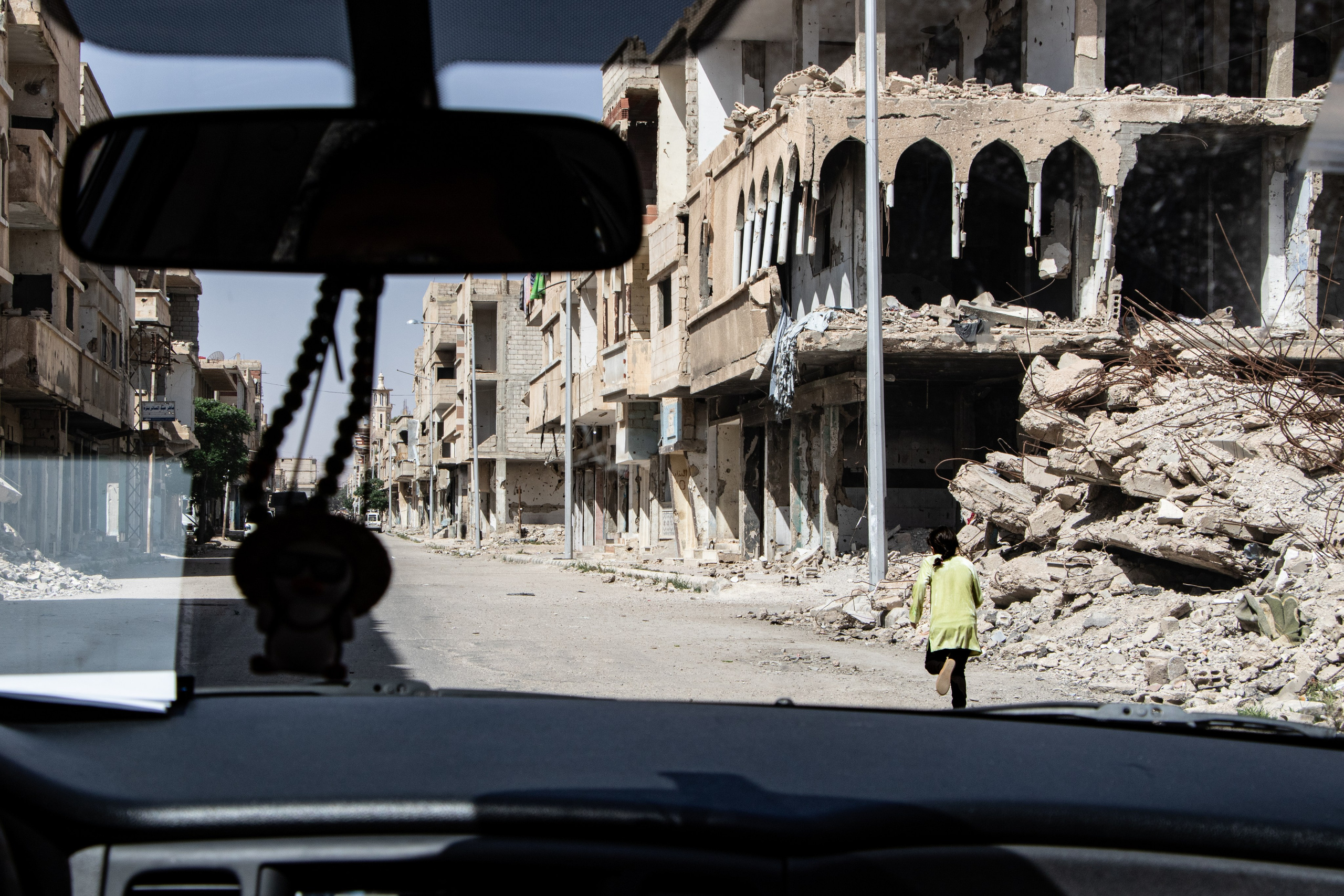 Une jeune fille court à travers les ruines de la ville de Palmyre, aujourd’hui sous contrôle russe, témoignant de la juxtaposition entre dévastation historique et présence militaire actuelle.