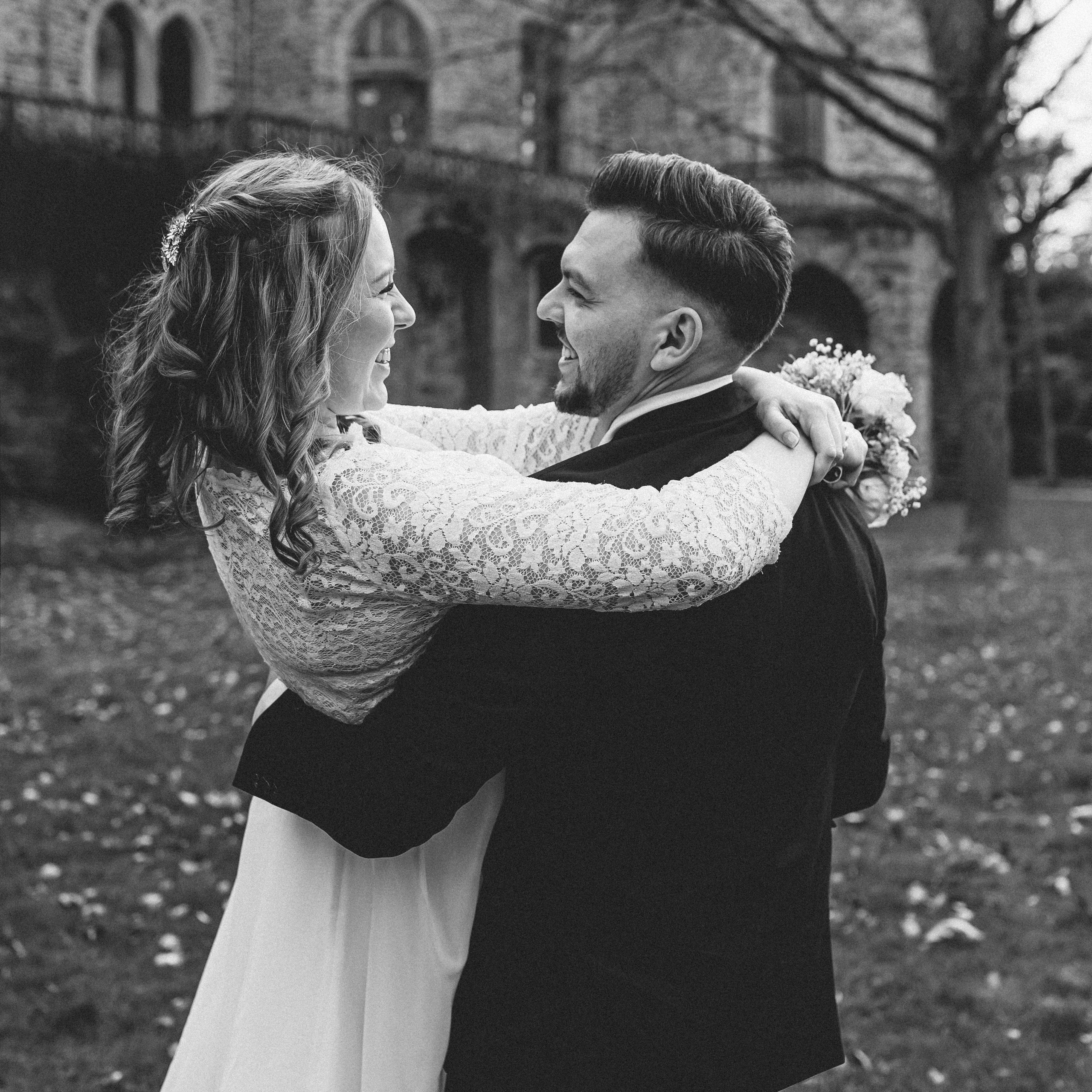 Braut und Bräutigam in einem romantischen Augenblick, der Bräutigam trägt seine Braut auf die Hände, während sie in Liebe strahlen