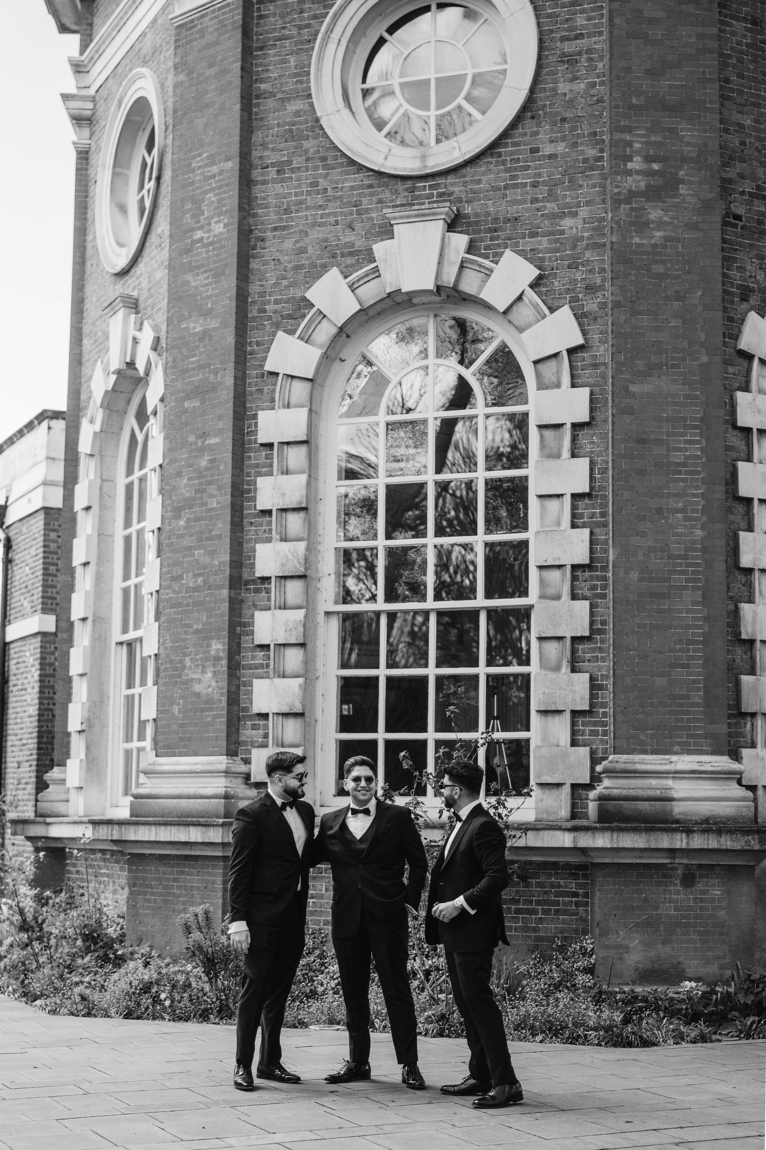 groom in black and white photo smiling with the family at the venue