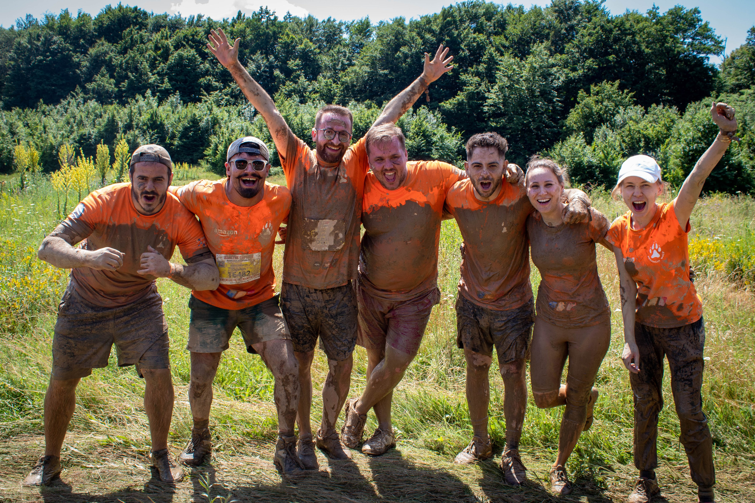 Team of runners flexing and celebrating after completing a muddy outdoor race.