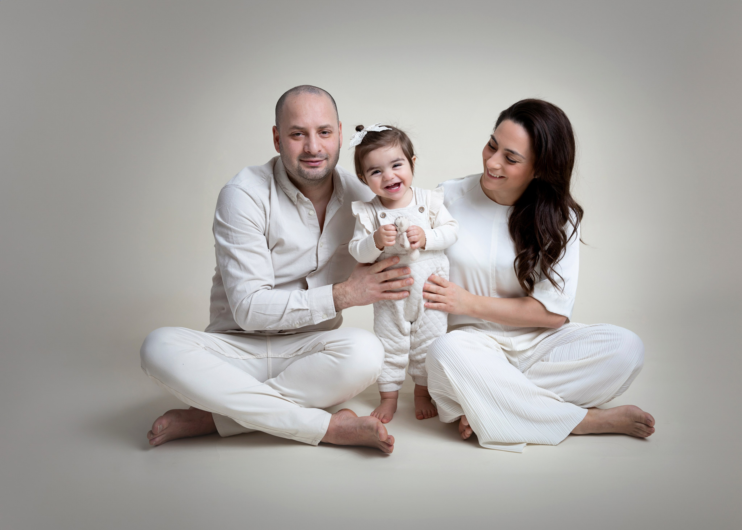 Familjefotografering i studion fångar ögonblicket av lycka med barn, mamma och pappa tillsammans.