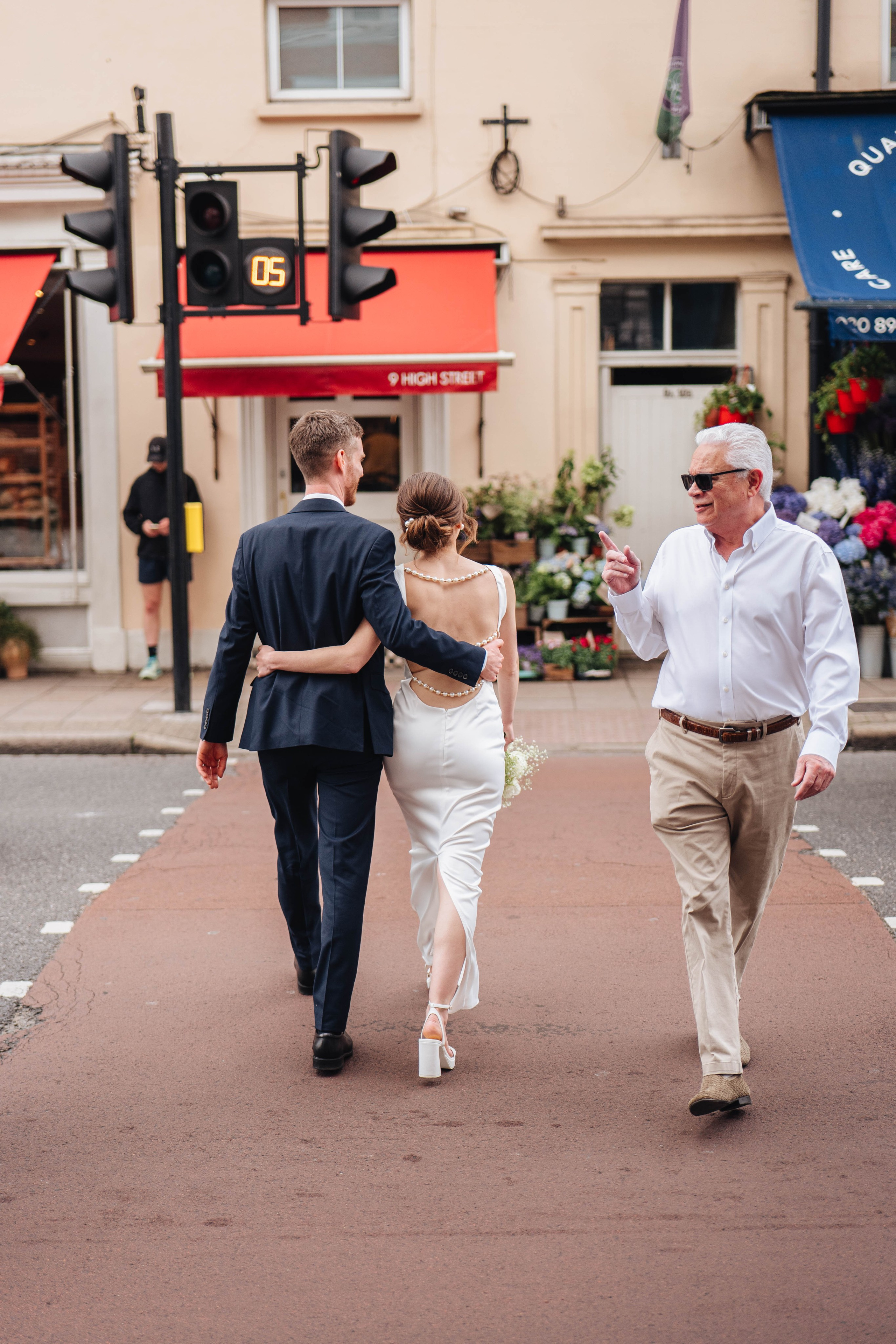 man pointing with his finger on the bride and groom crossing the road