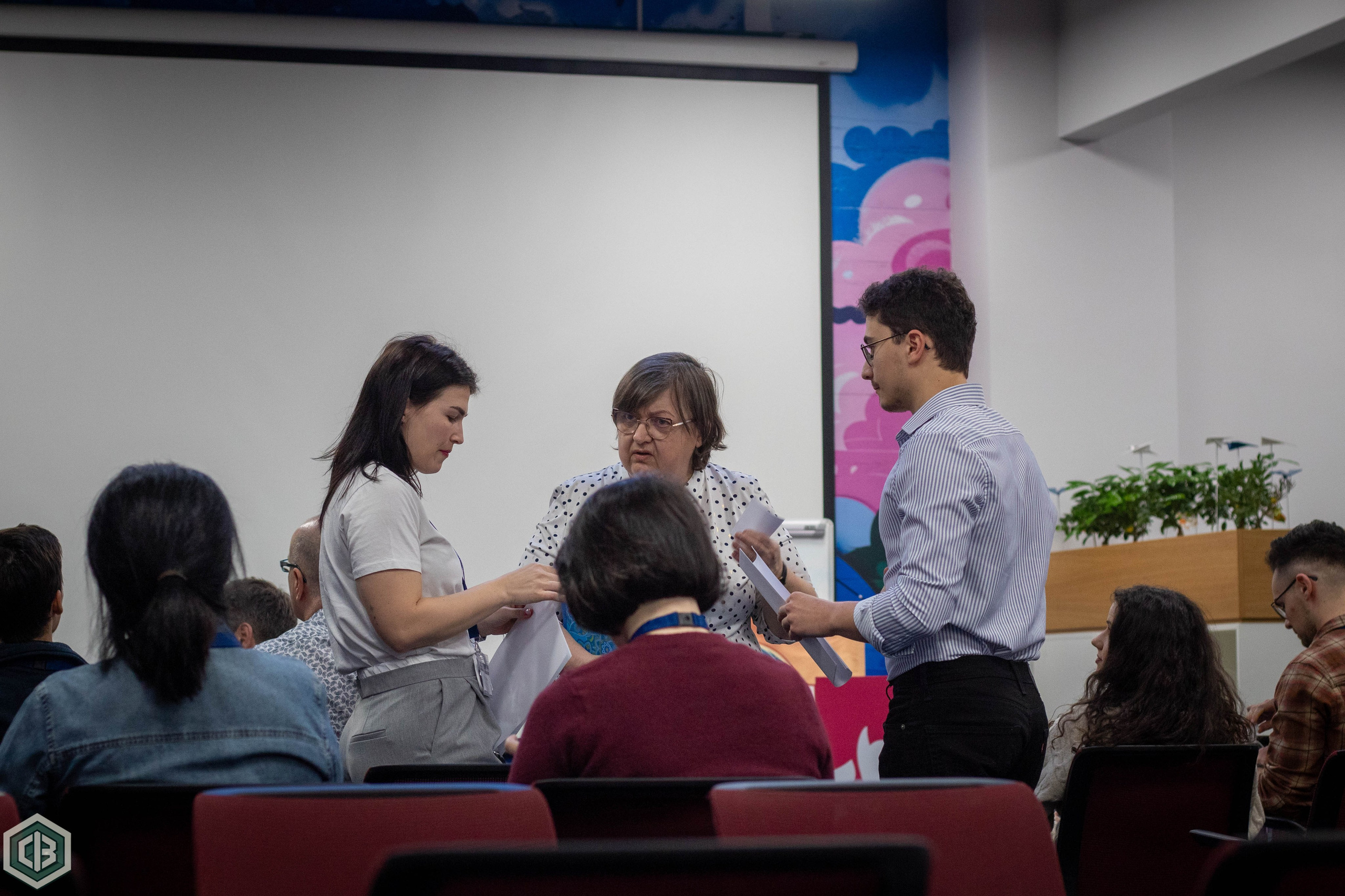 Man standing and speaking in front of a seated audience during an event.