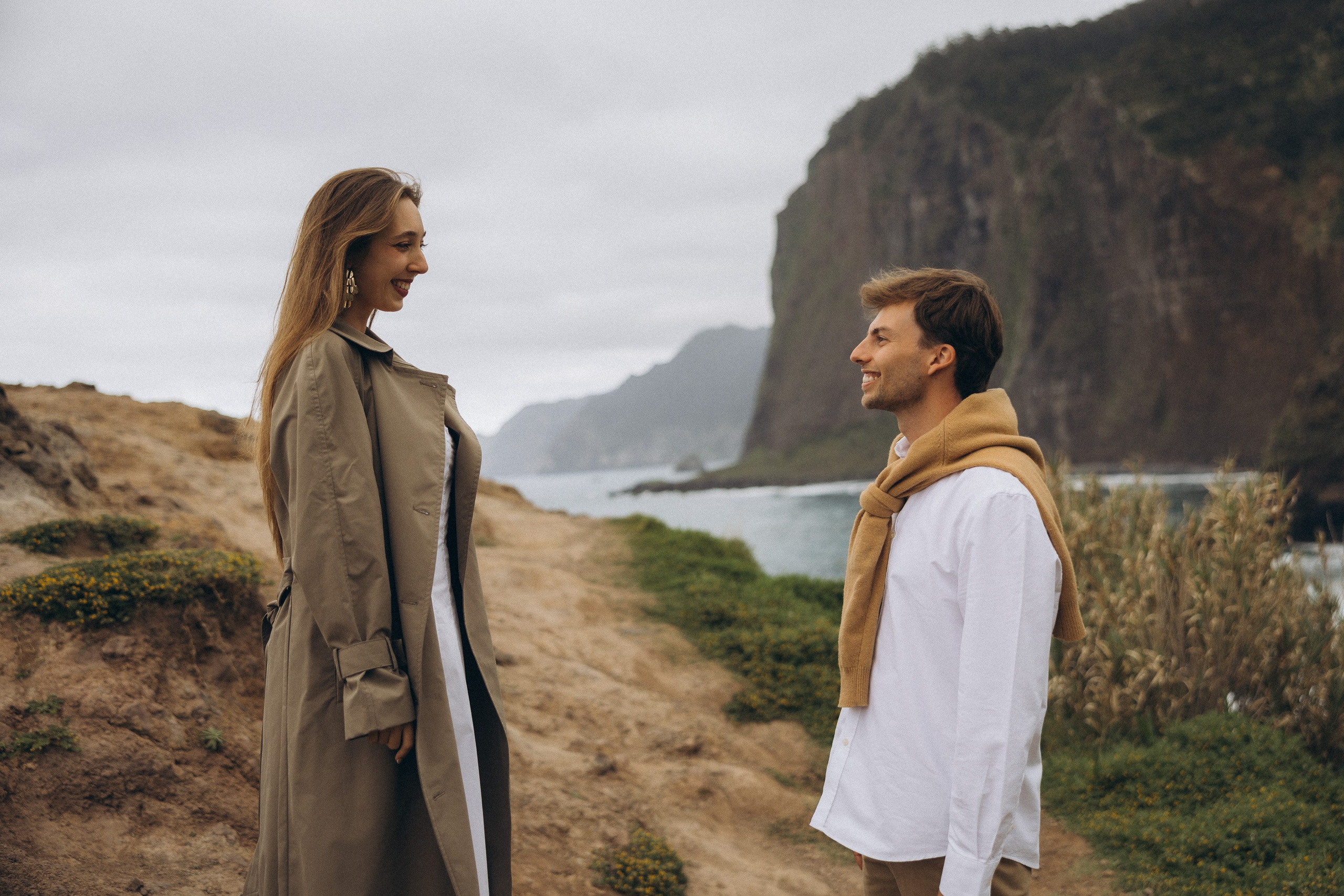 Beautiful engagement moment by the ocean in Madeira, Portugal, as one partner kneels to propose while waves crash in the background