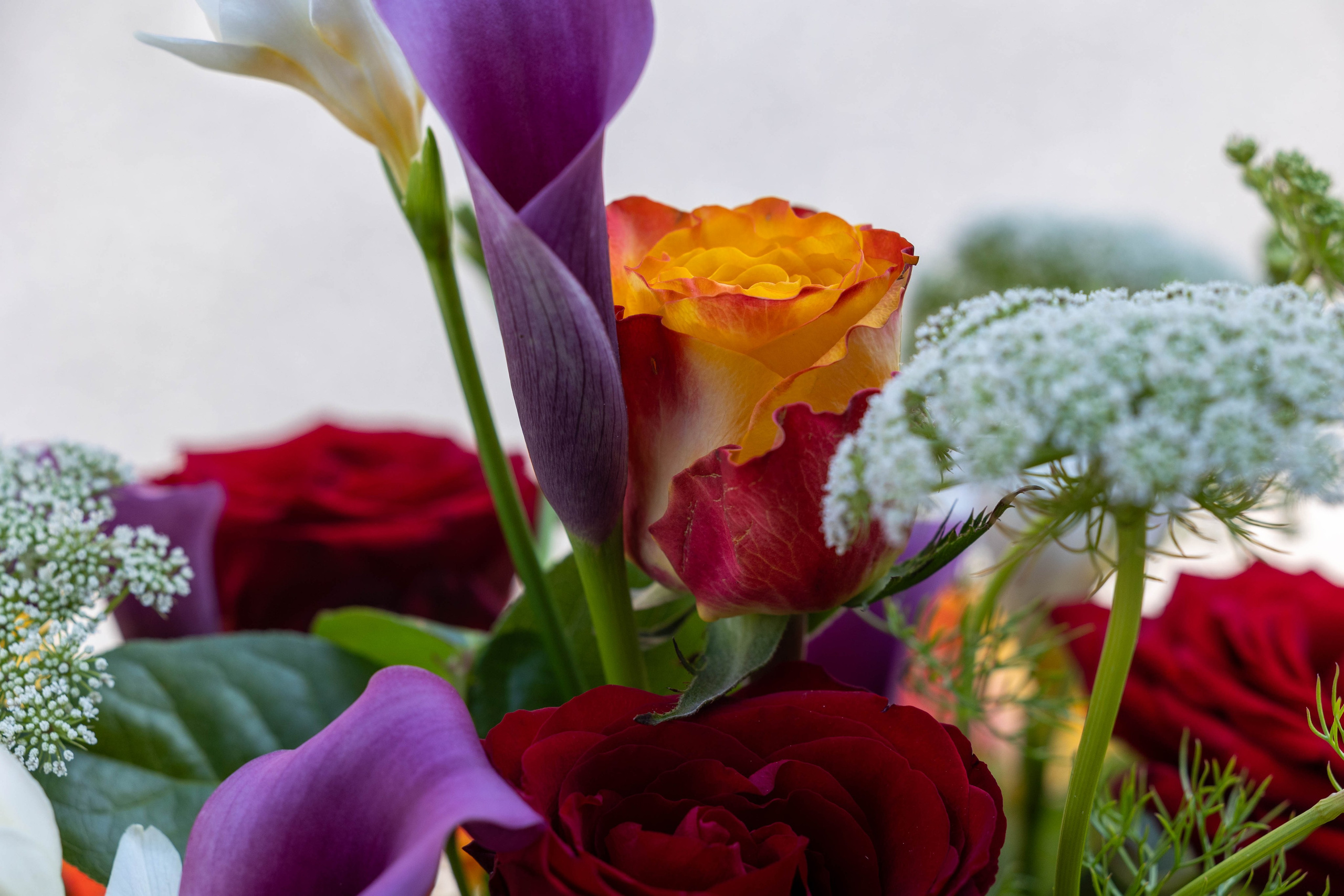 Blomsterne er arrangeret tæt langs hele kistelåget, hvilket skaber en fyldig og overdådig kiste. De smukke nuancer af grønt, hvidt og gult er harmonisk kombineret med sæsonens blomster. Denne unikke farvepalette fremstår elegant i kirkerummet.