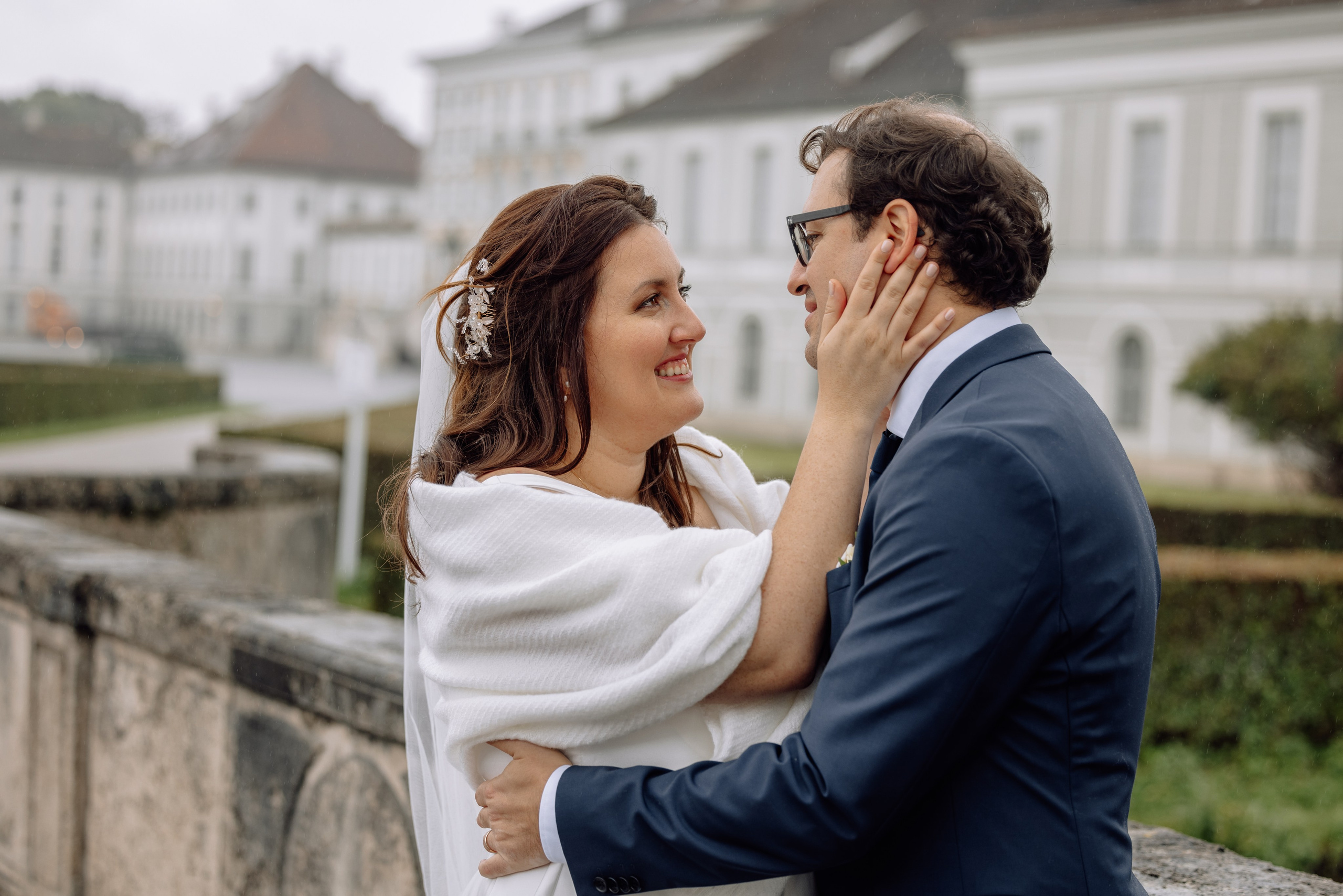 Braut berührt das Gesicht des Bräutigams vor dem Schloss Nymphenburg