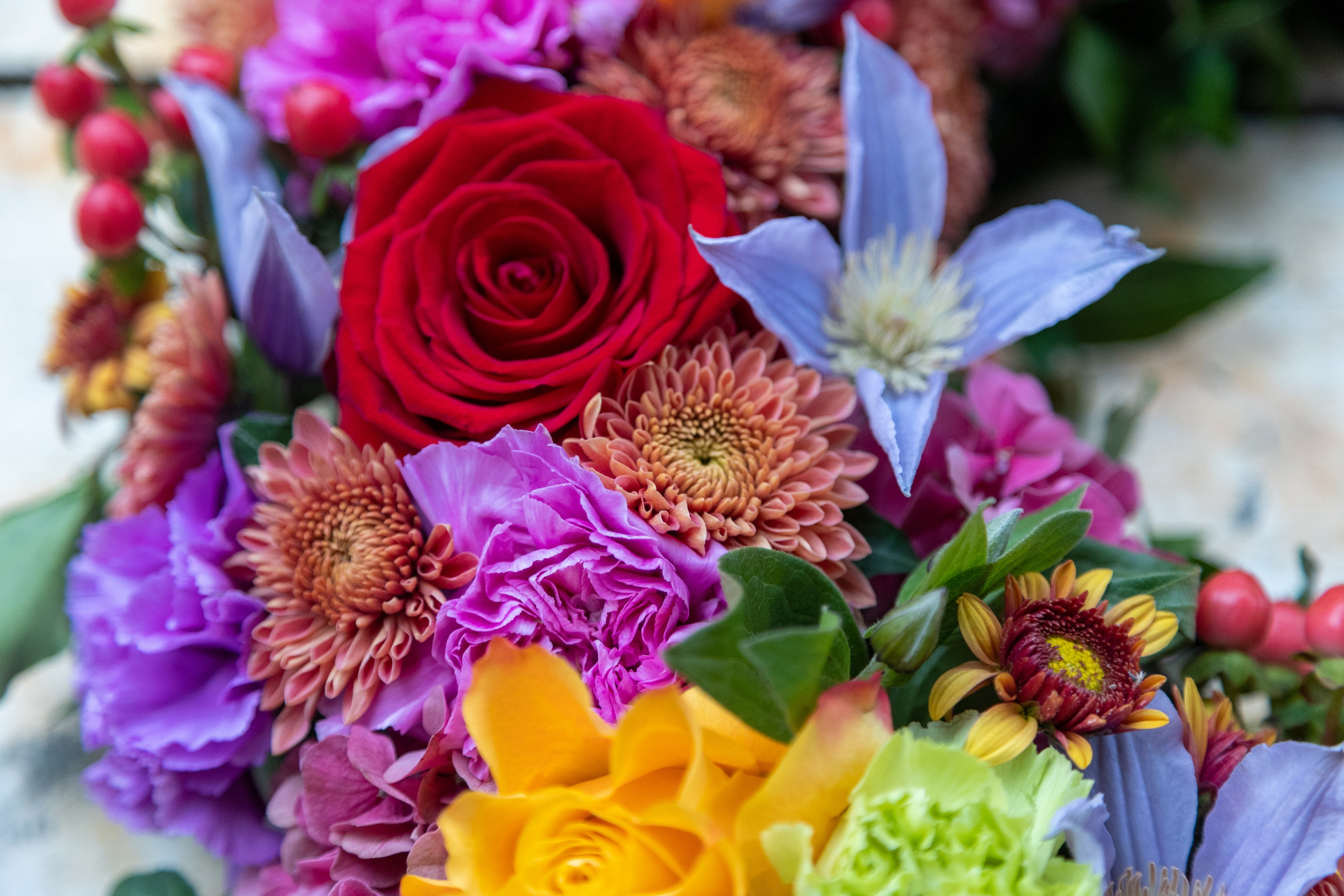 Hjerte, hvor blomsterne sidder tæt sammen i blå, orange og rødlige toner. Små og store blomster er kombineret i et flot sammenspil, som giver et levende udtryk. En sidste kærlig hilsen, som tager sig smukt ud på kirkegulvet.