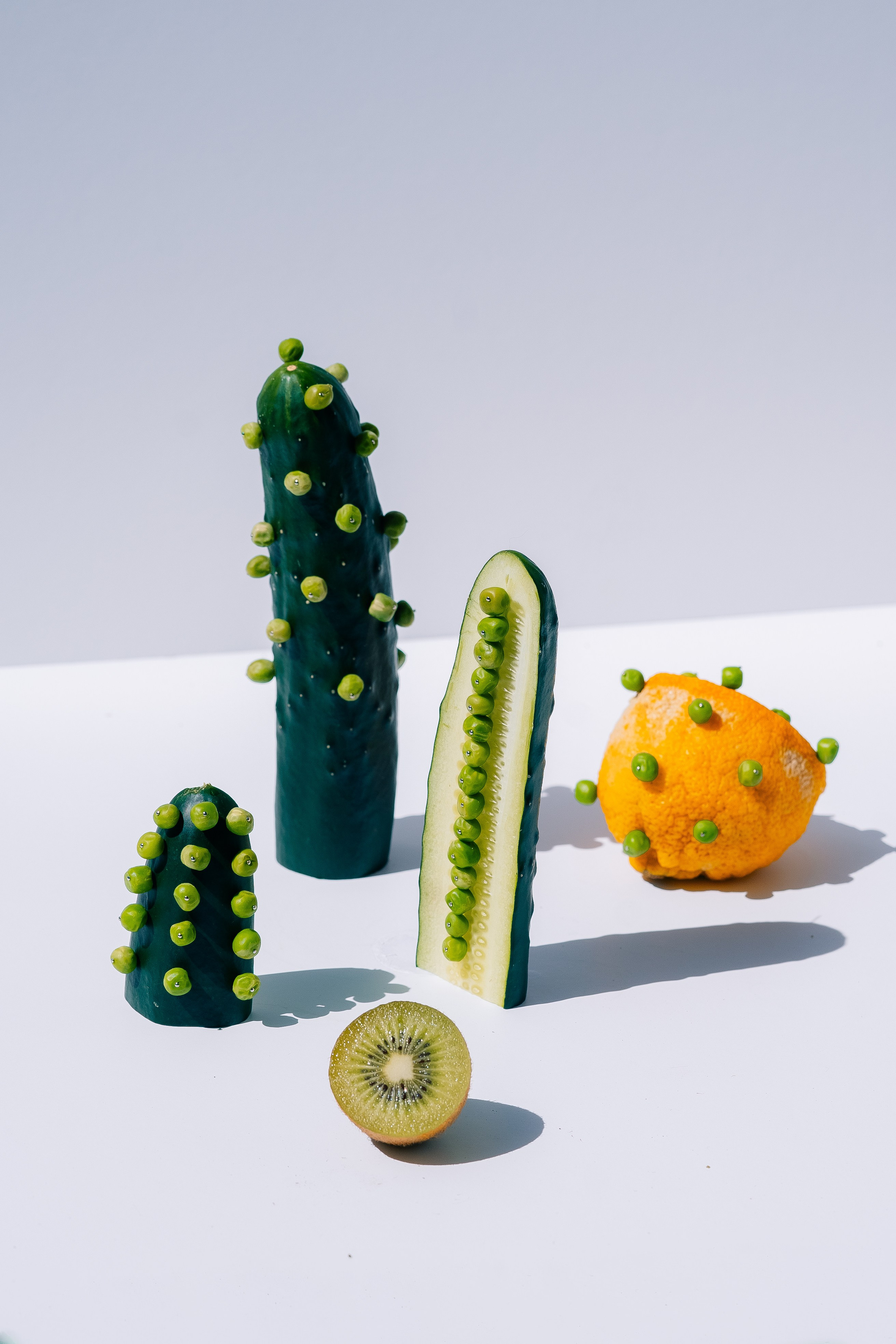 Arranjo criativo de vegetais e frutas. Arranjo exclusivo de pepinos, ervilhas, limão e kiwi em um fundo branco.