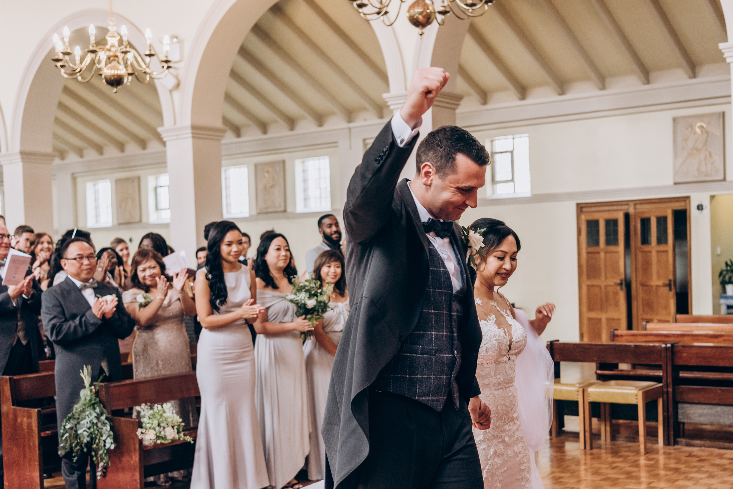 groom happily is putting hands up after wedding ceremony 