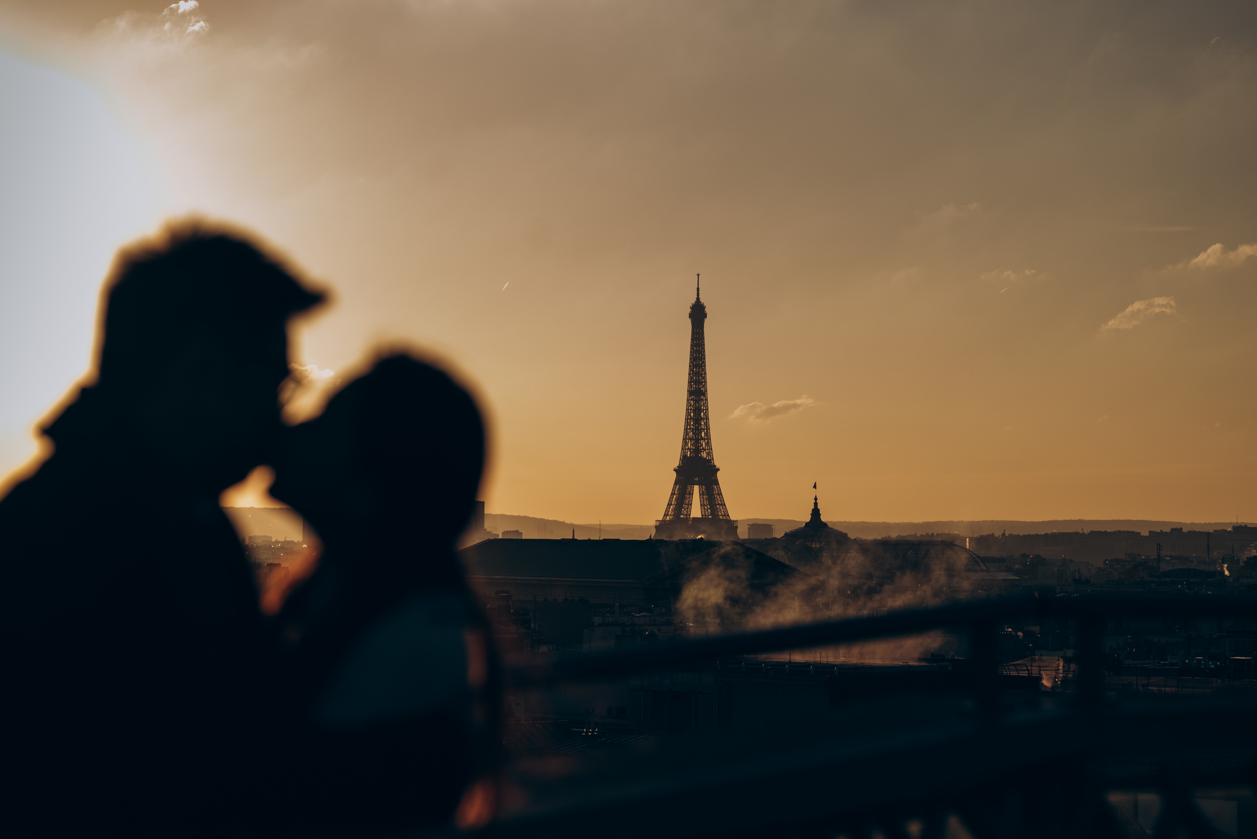 couple is kissing with sunset lights at front of Eiffel Tower 