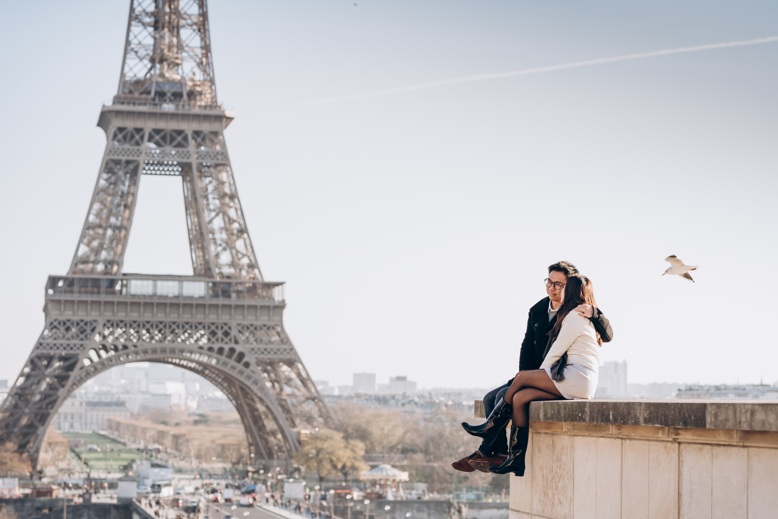 couple is sitting at front of Eiffel Tower 