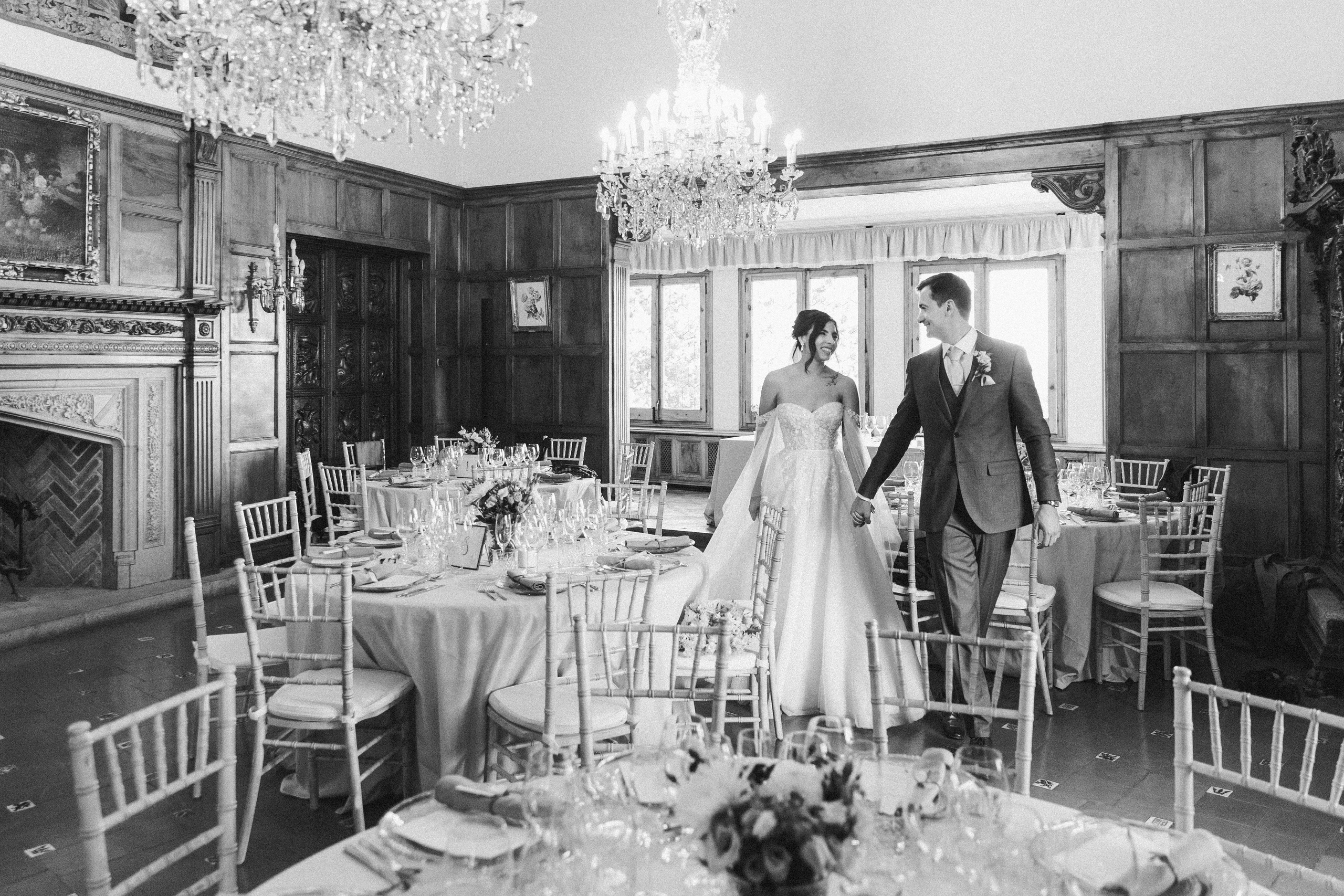 Groom and bride walking among tables prepared for the wedding dinner in the luxury wedding venue in Barcelona. 