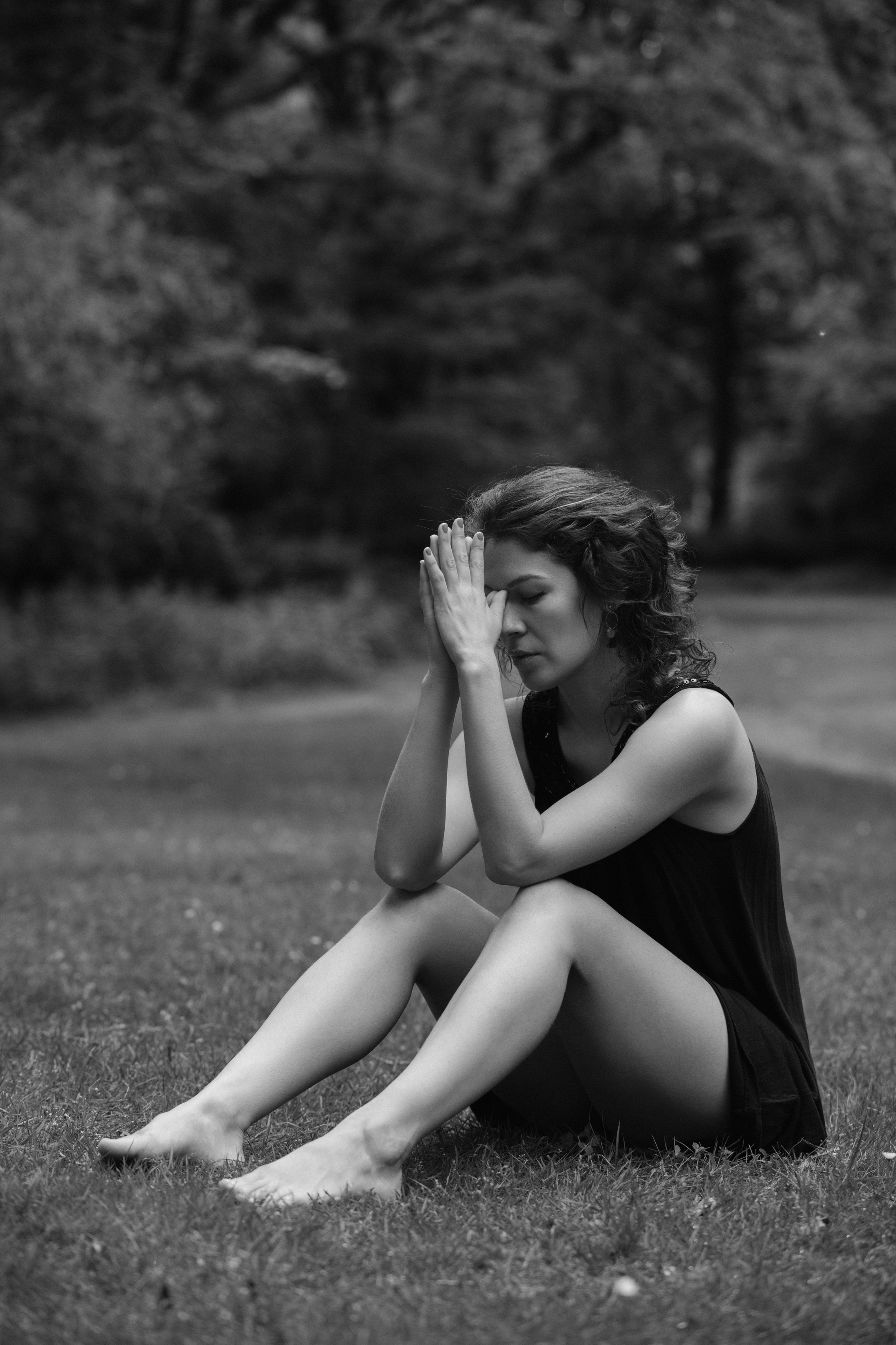 Sitzende Frau in nachdenklicher Pose auf Gras, Tiergarten Berlin