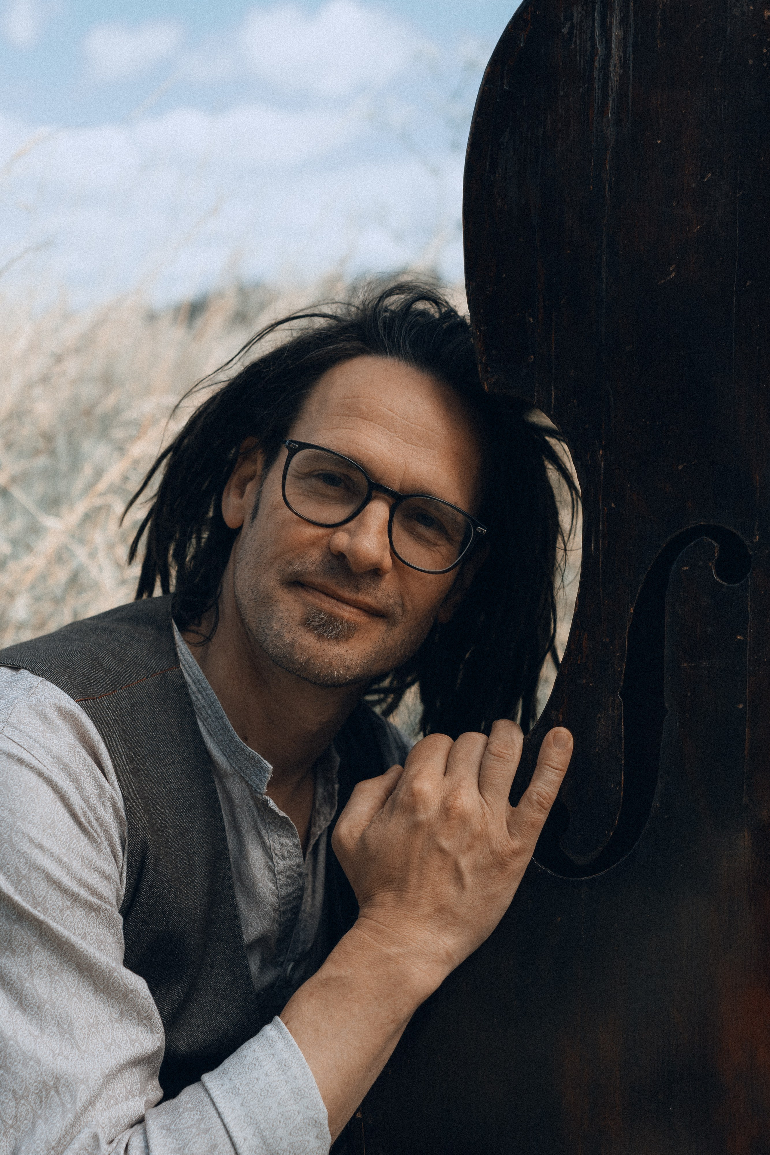 Kontrabassist lehnt am Instrument, Portraitaufnahme