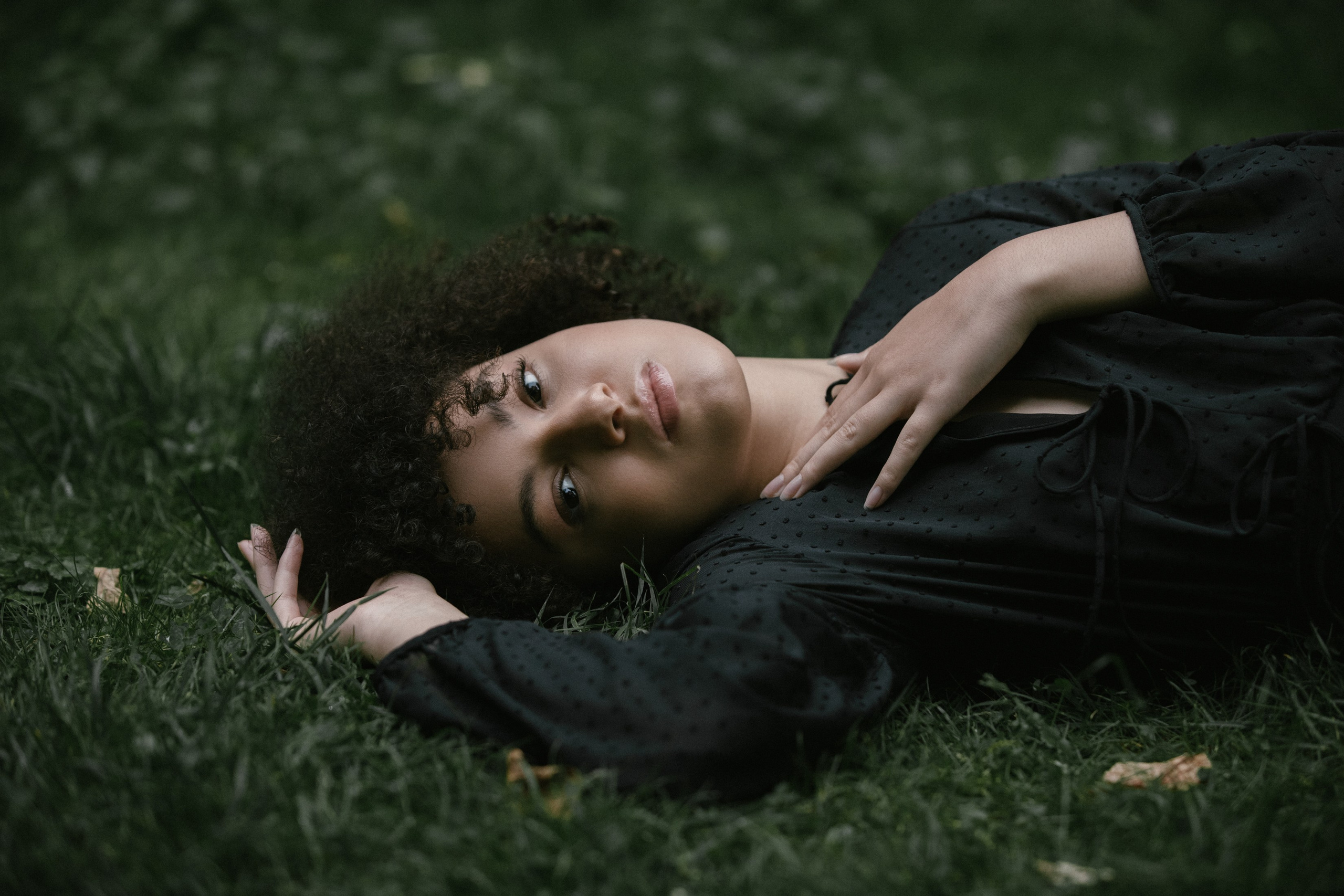 Relaxed outdoor portrait, woman lying on grass with tilted head