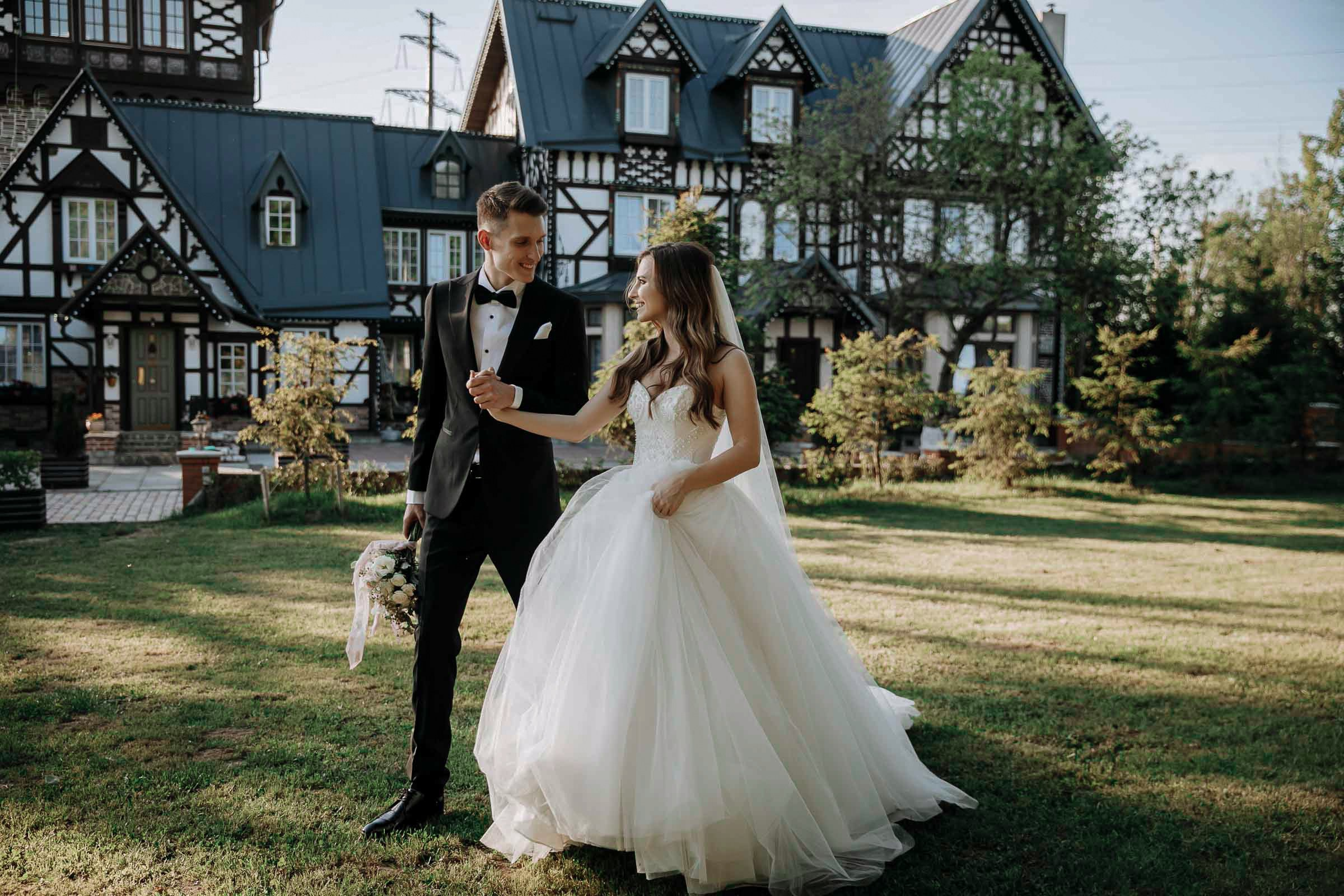 Bride and groom stroll in gardens with grand house, by Tanya Bodgan, Exeter wedding photographer.