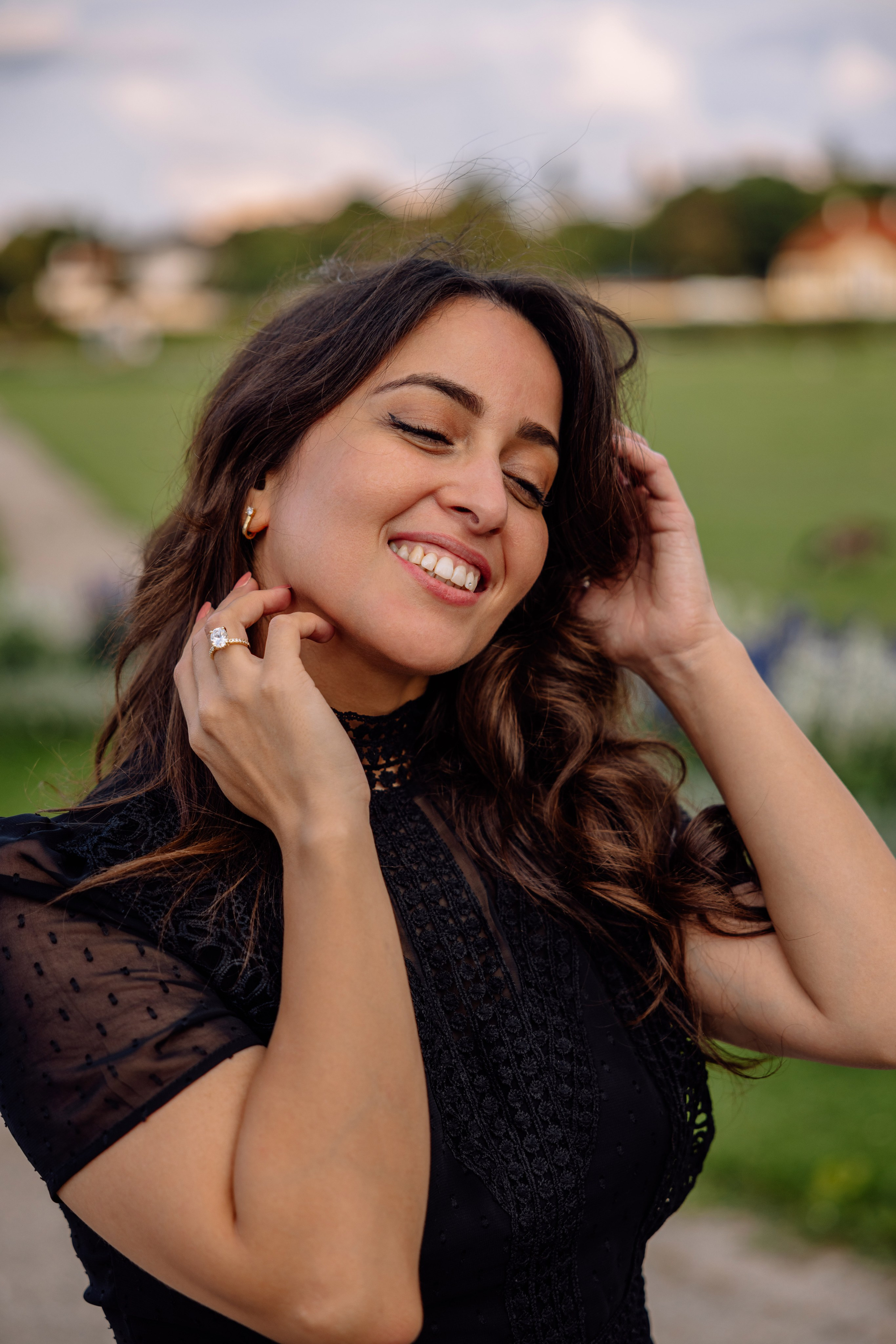 Braut spielt mit ihren Haaren und lacht vor dem Schloss Nymphenburg