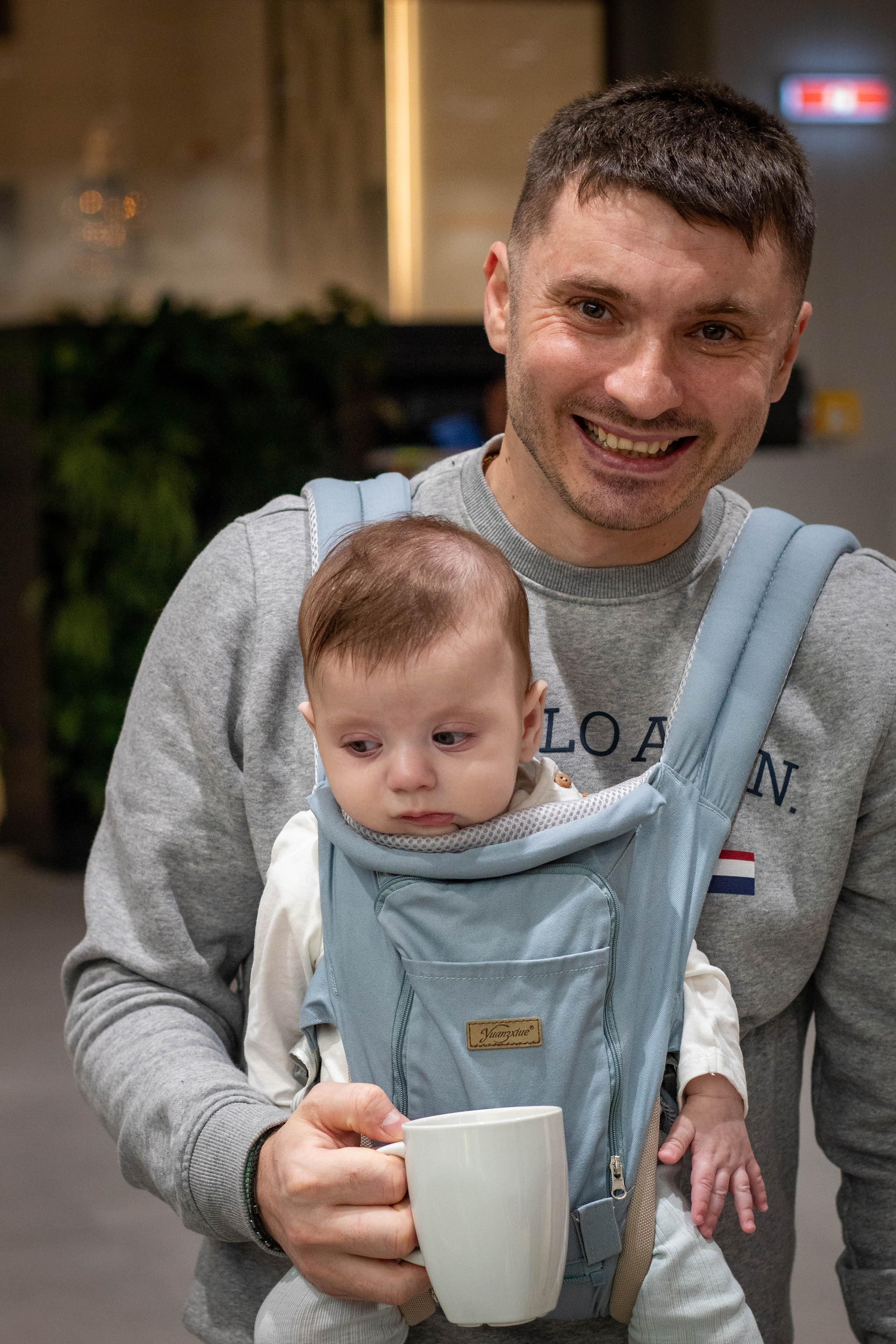 Smiling man holding a toddler girl on his lap, both looking at the camera.