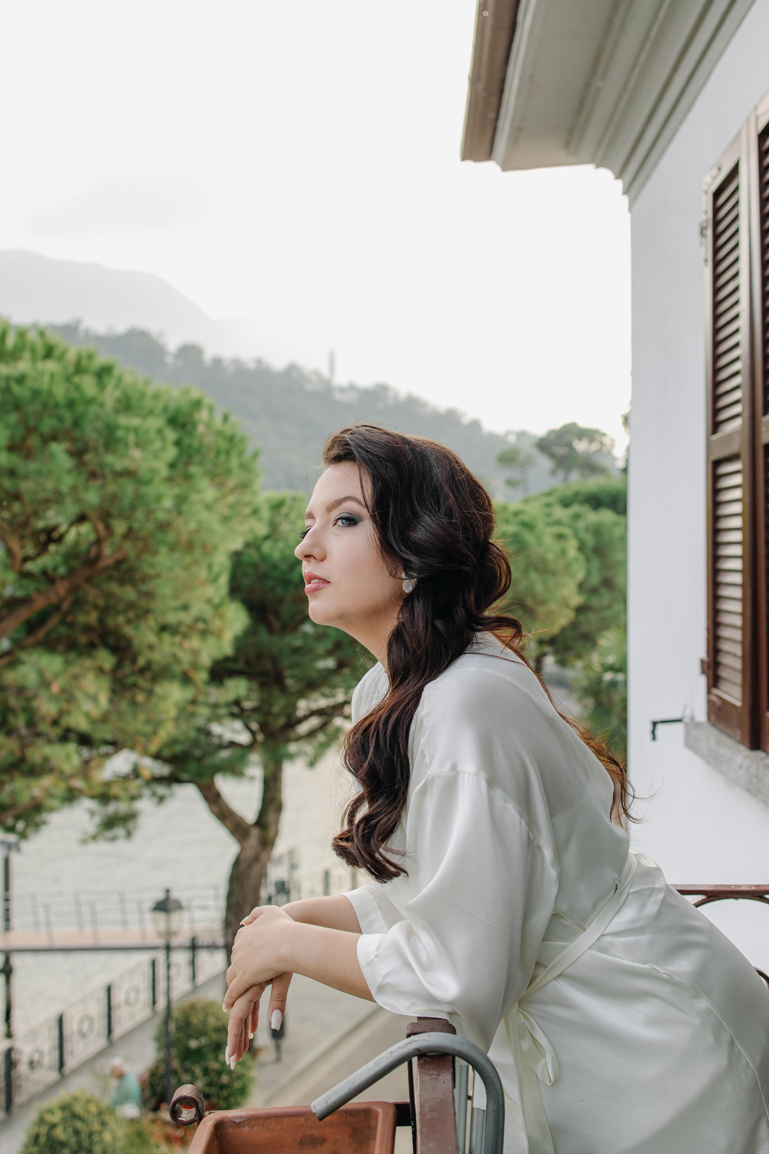 Невеста в атласном халатике на балконе смотрит на озеро