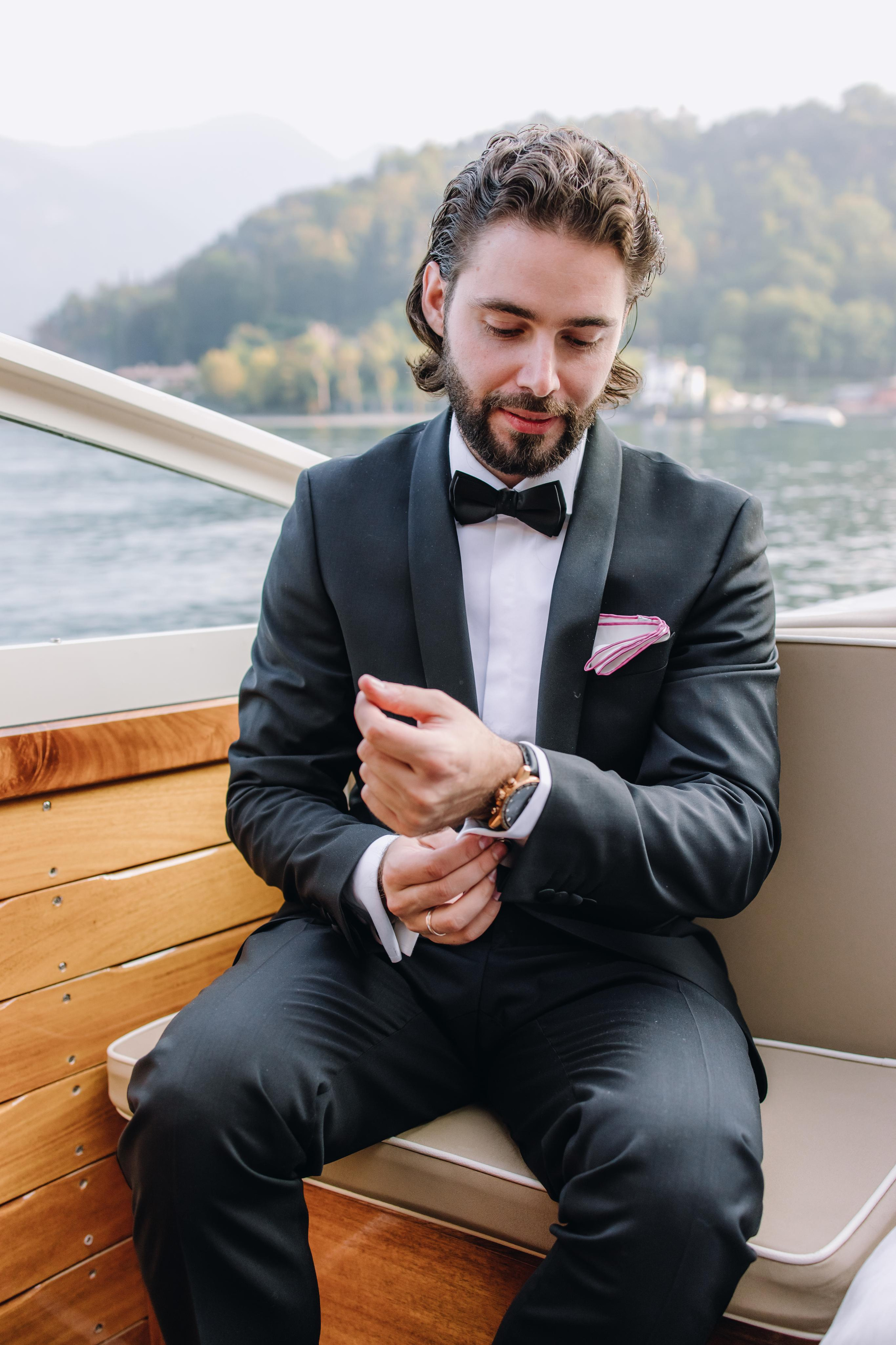 Жених на лодке на озере Комо застегивает часы