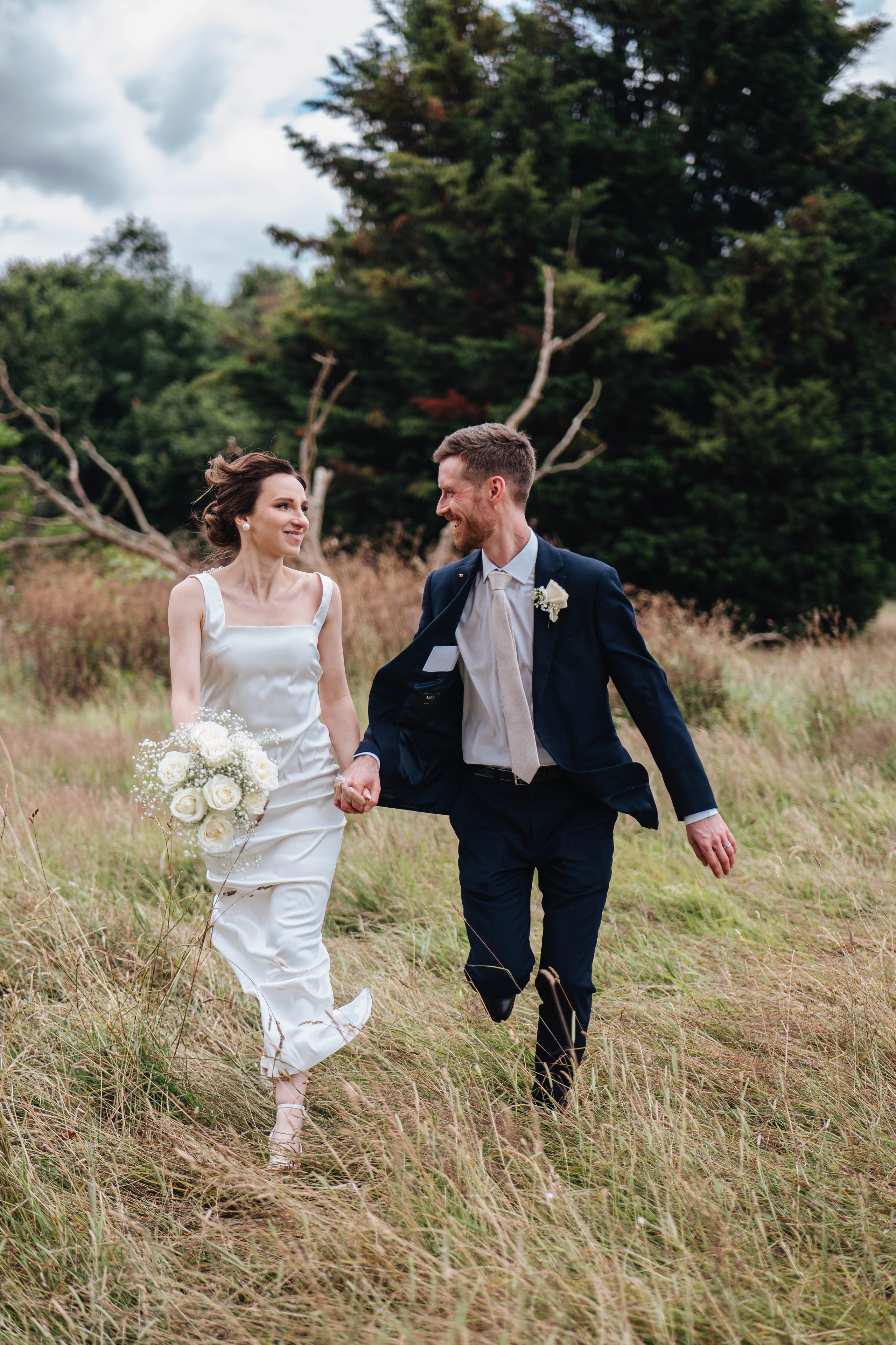 bride and groom running while holding hands and looking at each other