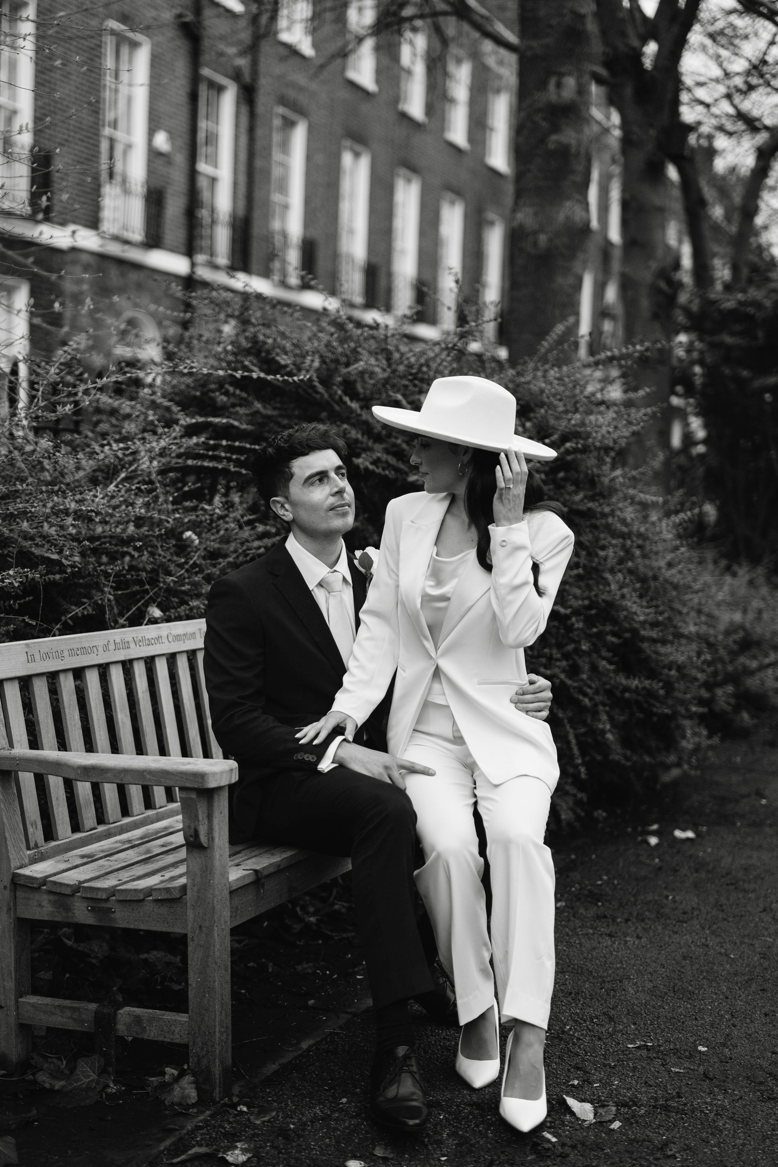 Stylish wedding in Islington, white women costume and white hat, sitting on a bench