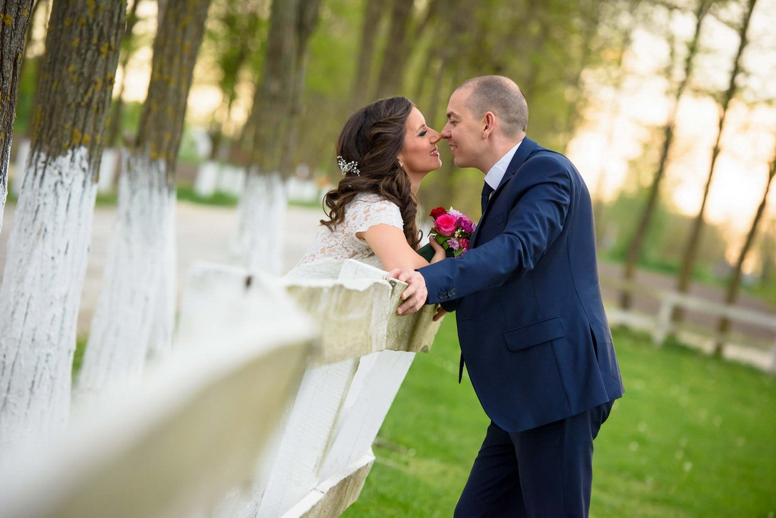 Romantičan poljubac mladenaca kod ograde na salašu, okruženi prirodom – savršeni momenti