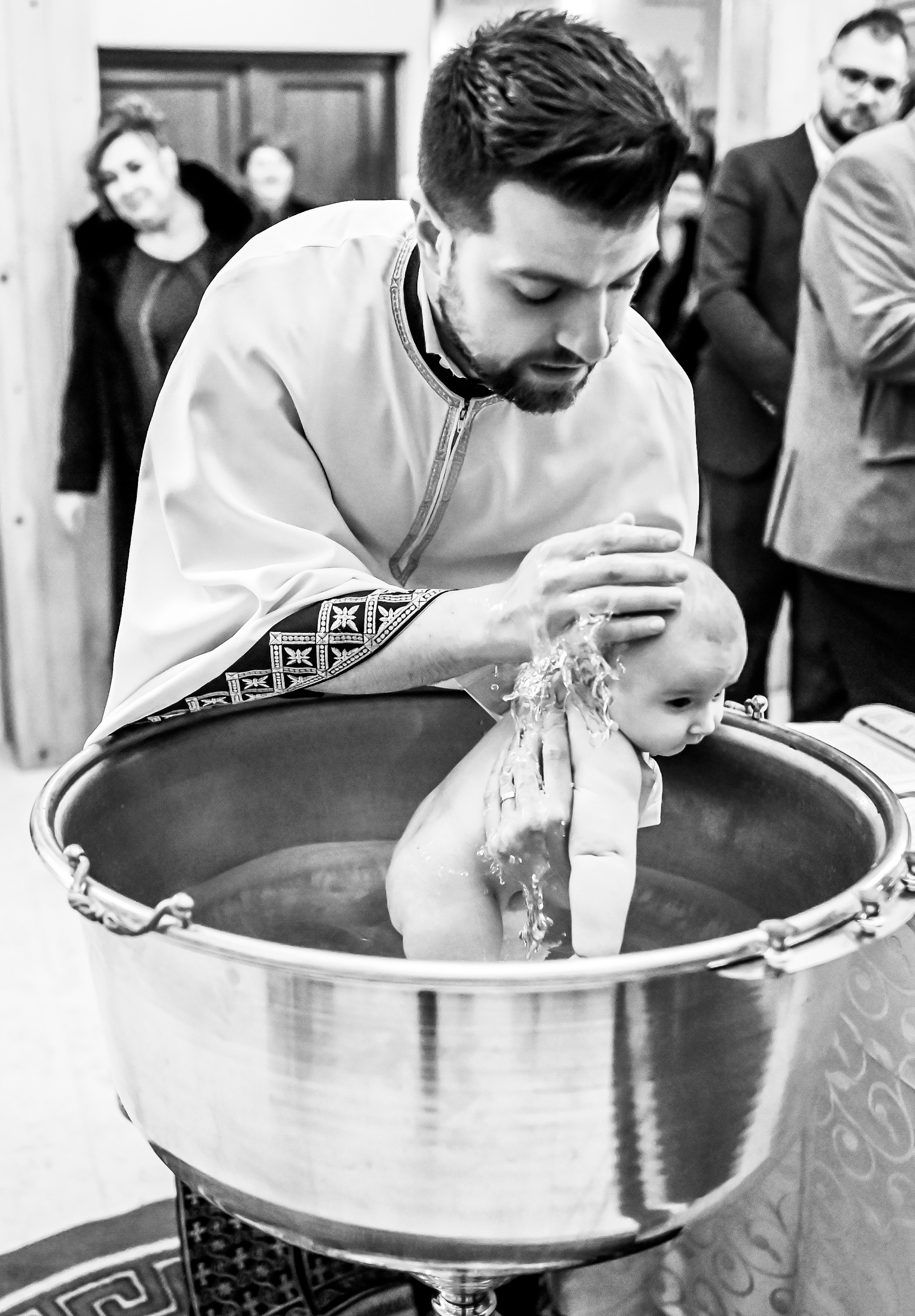 Copil în brațele preotului lângă cristelniță – cadru din ceremonia de botez Ana Maria Drăgan