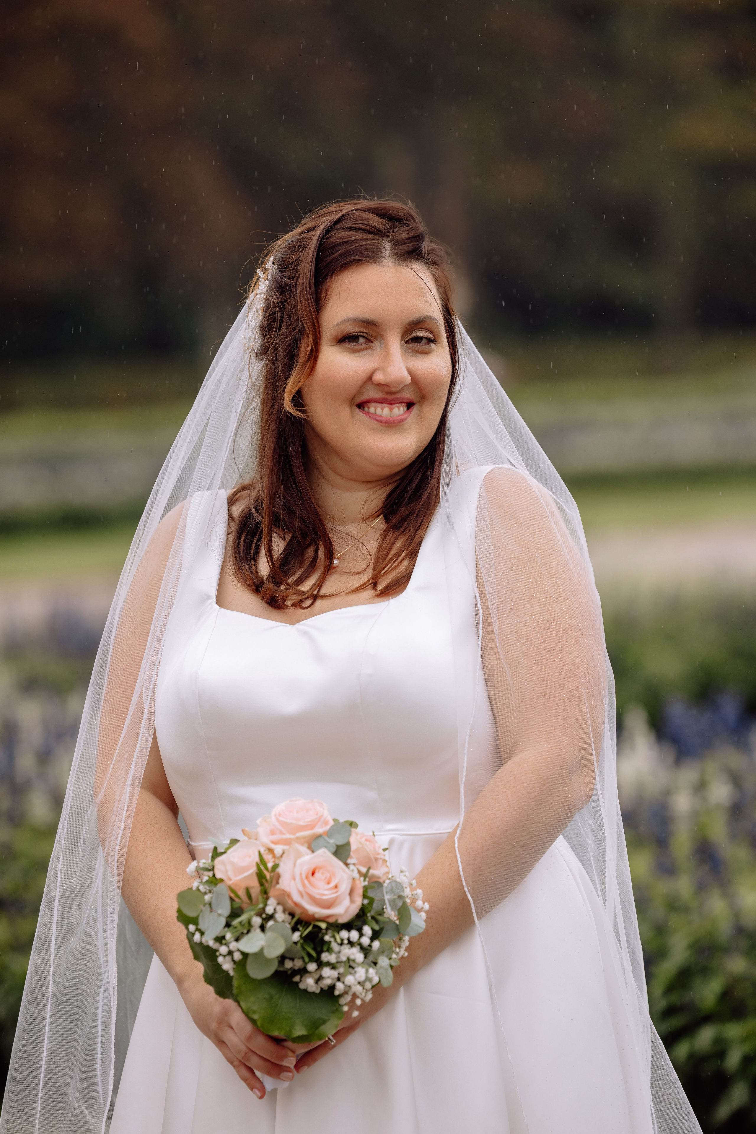 Braut lächelt und hält ihren Brautstrauß  vor dem Schloss Nymphenburg