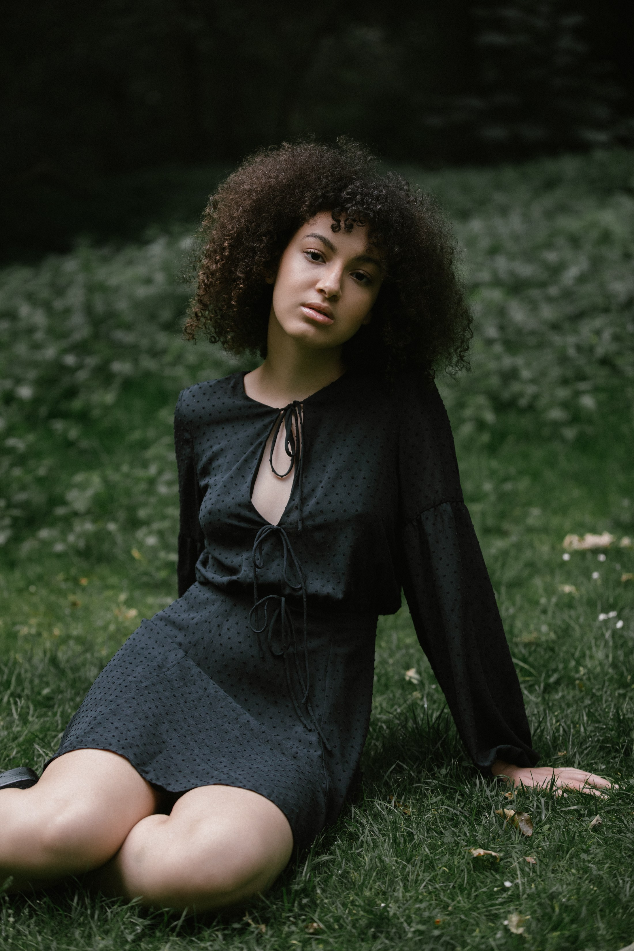 Natural light portrait, woman sitting on grass, direct gaze