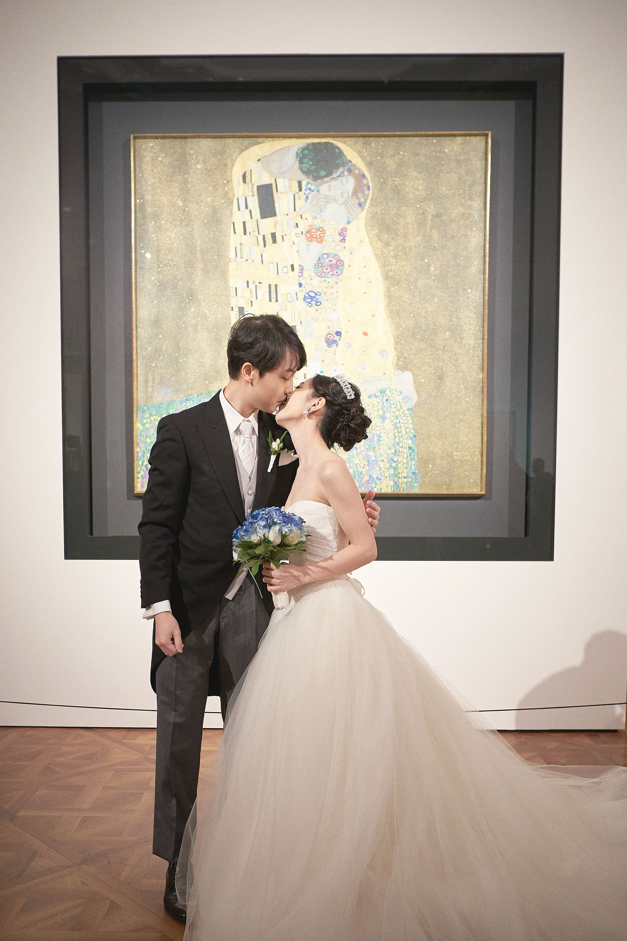 The bride and groom kiss in front of the famous Alfons Mucha painting that is in the collection of the Belvedere Palace.
