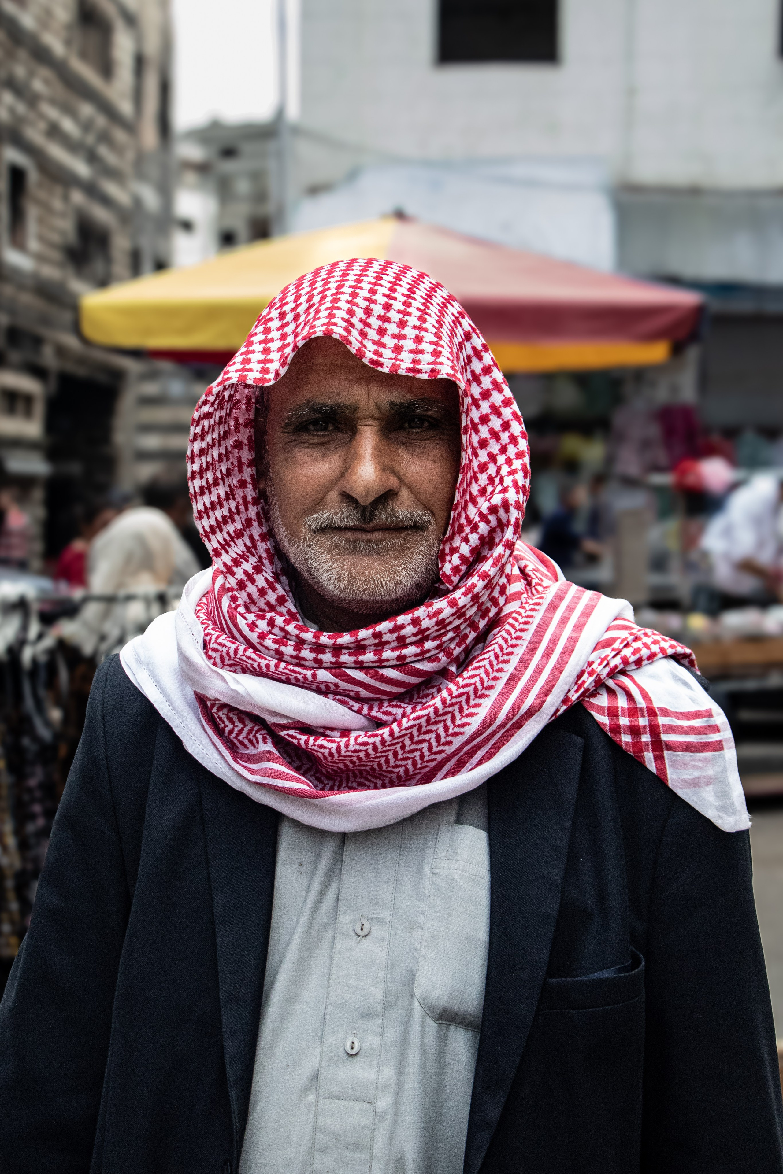 Portrait d’un homme dans le souk d’Alep, où, malgré les cicatrices laissées par la guerre, la vie continue de battre au rythme des échanges et de l’activité quotidienne.