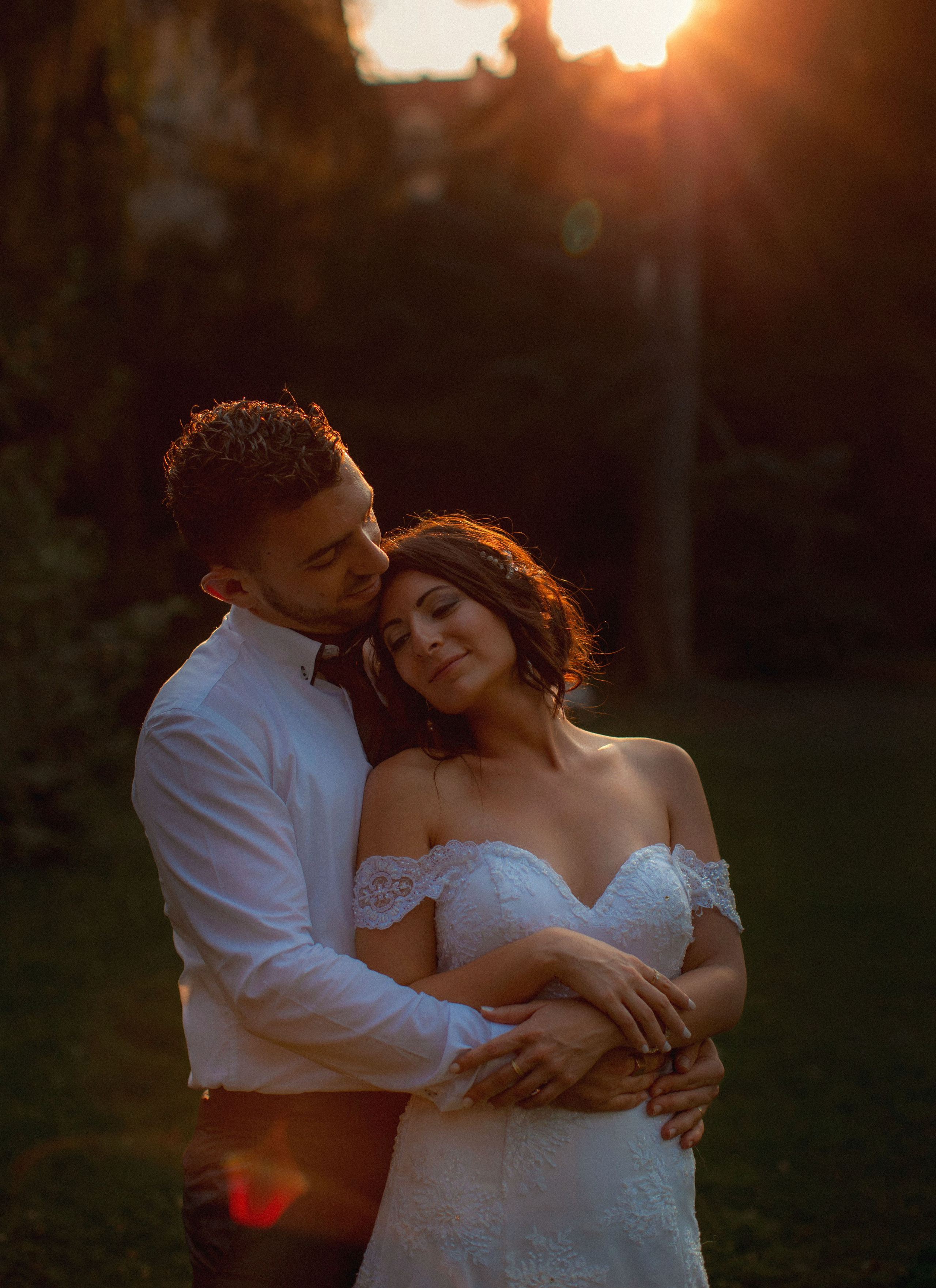 Young bride embraced by Israeli groom with sunset backdrop in a secret garden, Prague.