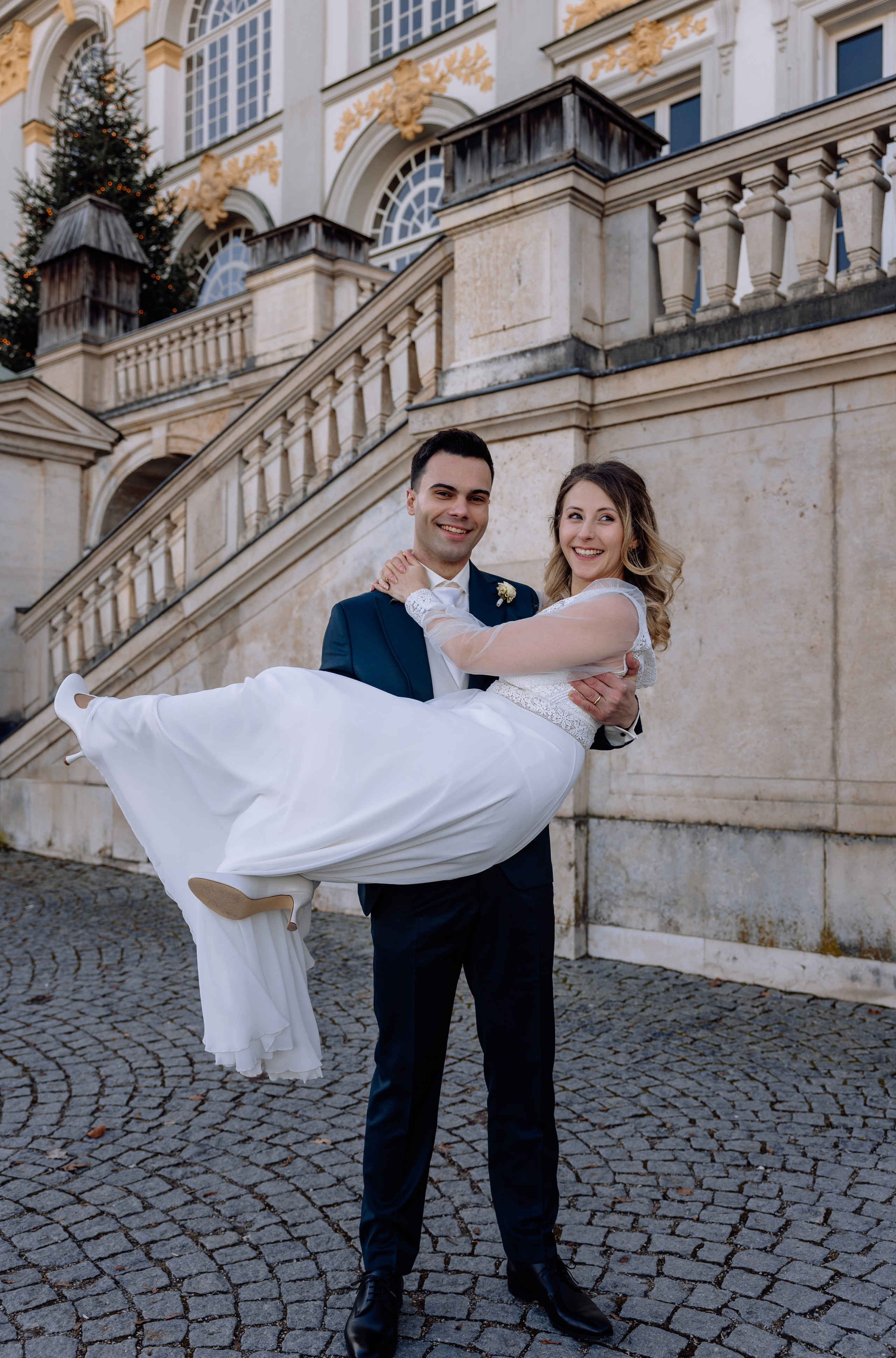 Braut wird auf Händen getragen und gedreht vor dem Schloss Nymphenburg