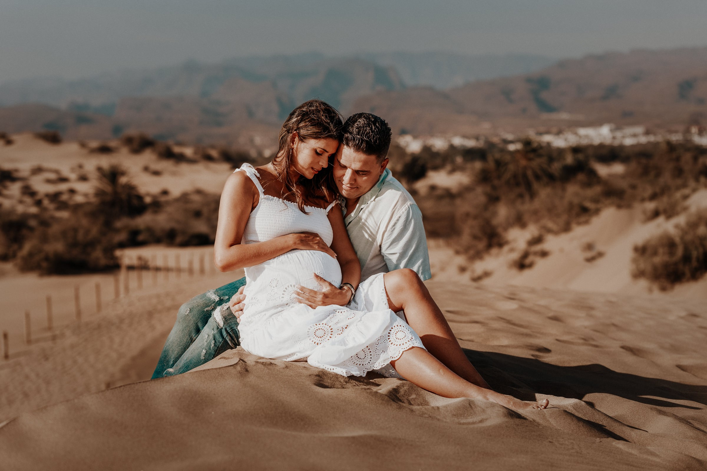 A couple is seated atop a sand duns Maspalomas while the woman is pregnant. Photo Shoot