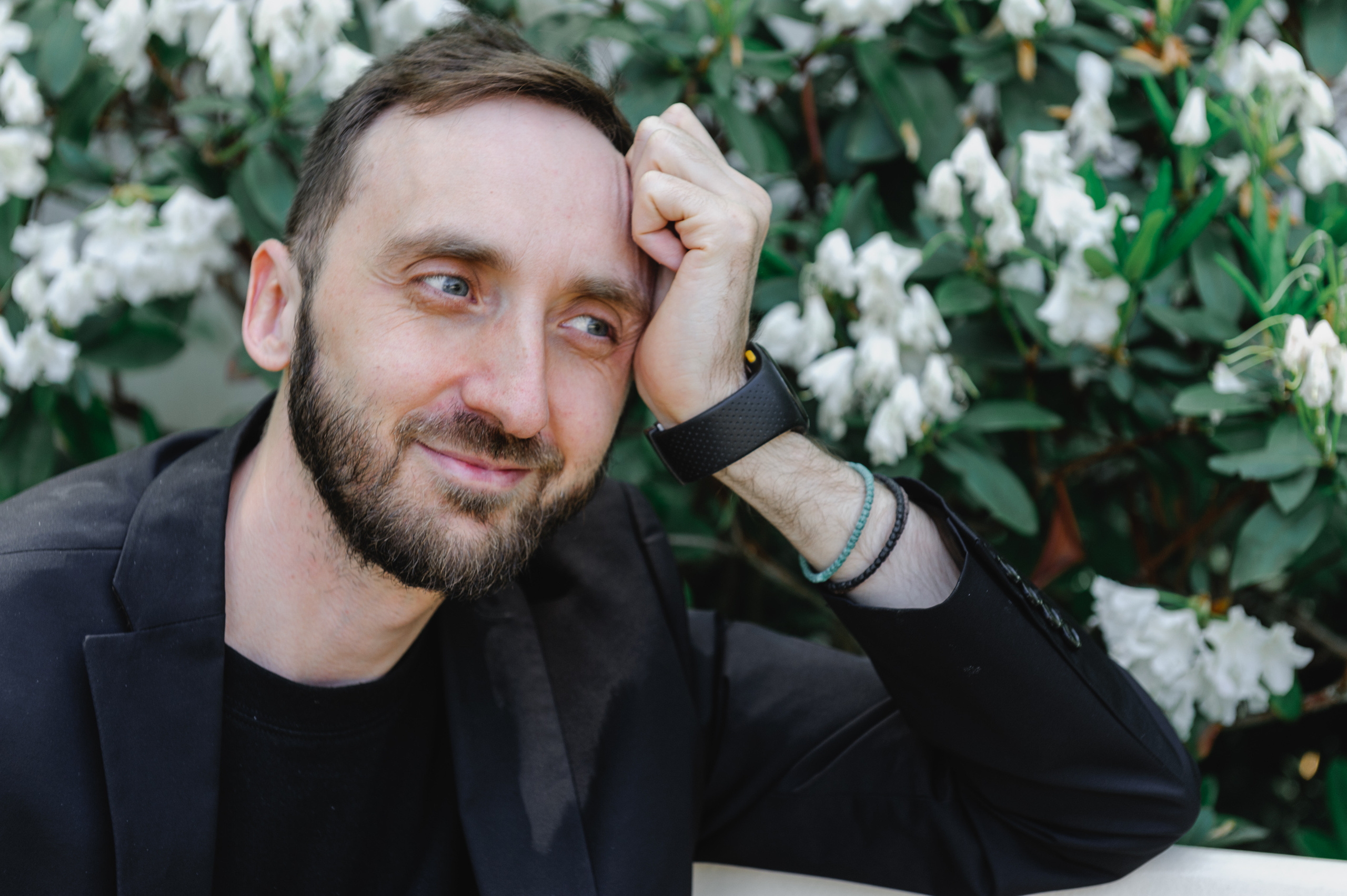 Искусствовед Дмитрий Солодкий задумался на скамейке на фоне цветов