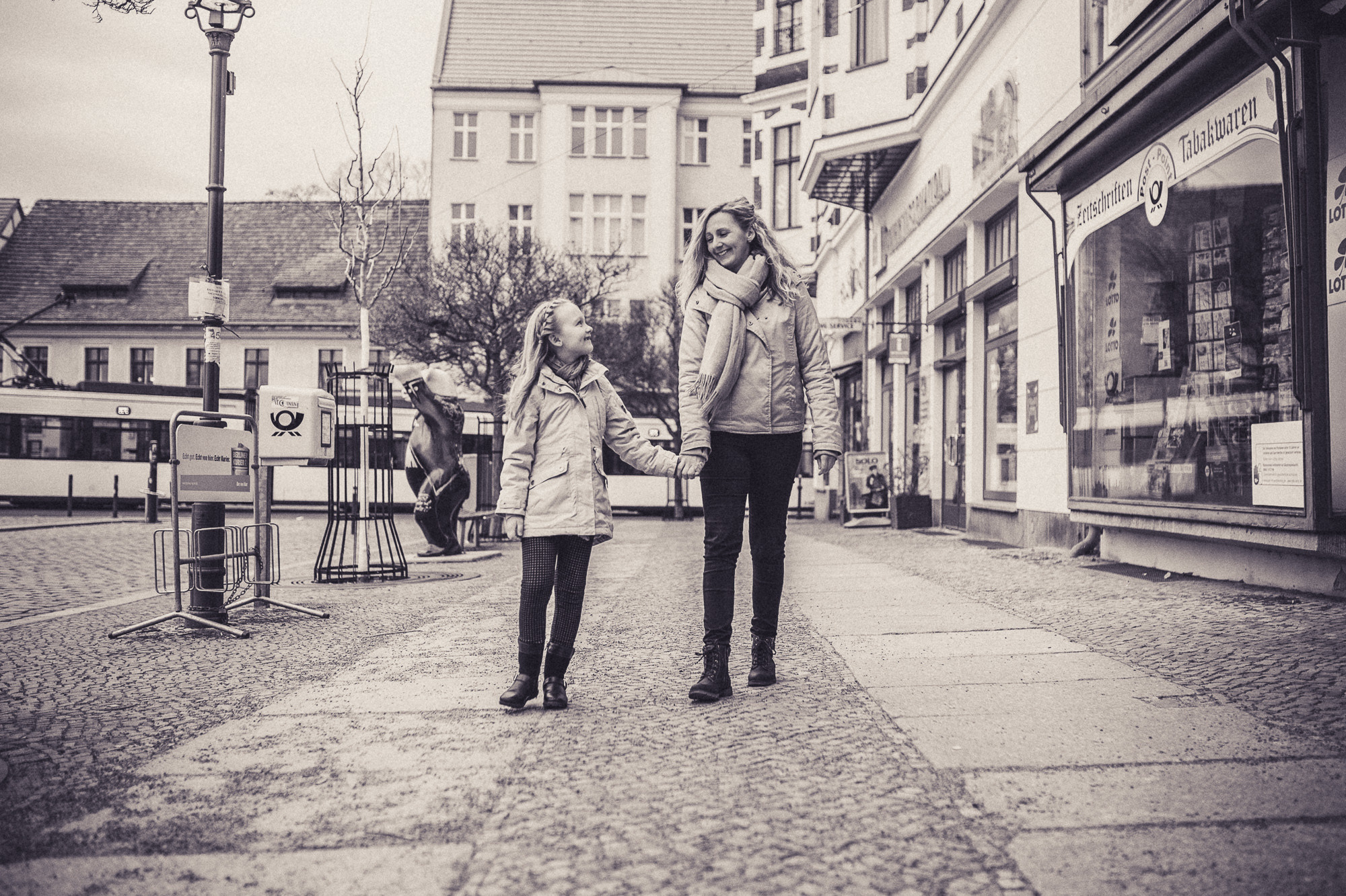 Mama und Tochter spazieren Hand an Hand in Altstadt