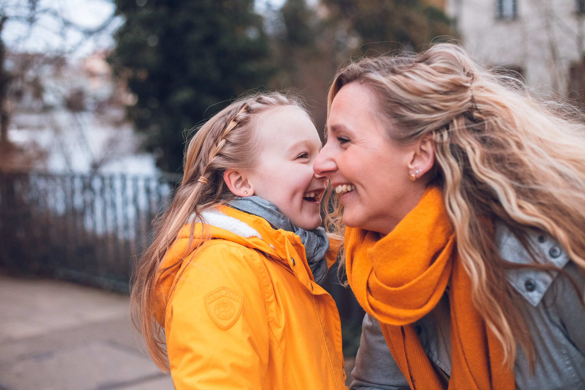 Mama mit gelbe Schall mit dem Kind in gelbe Jacke lacht