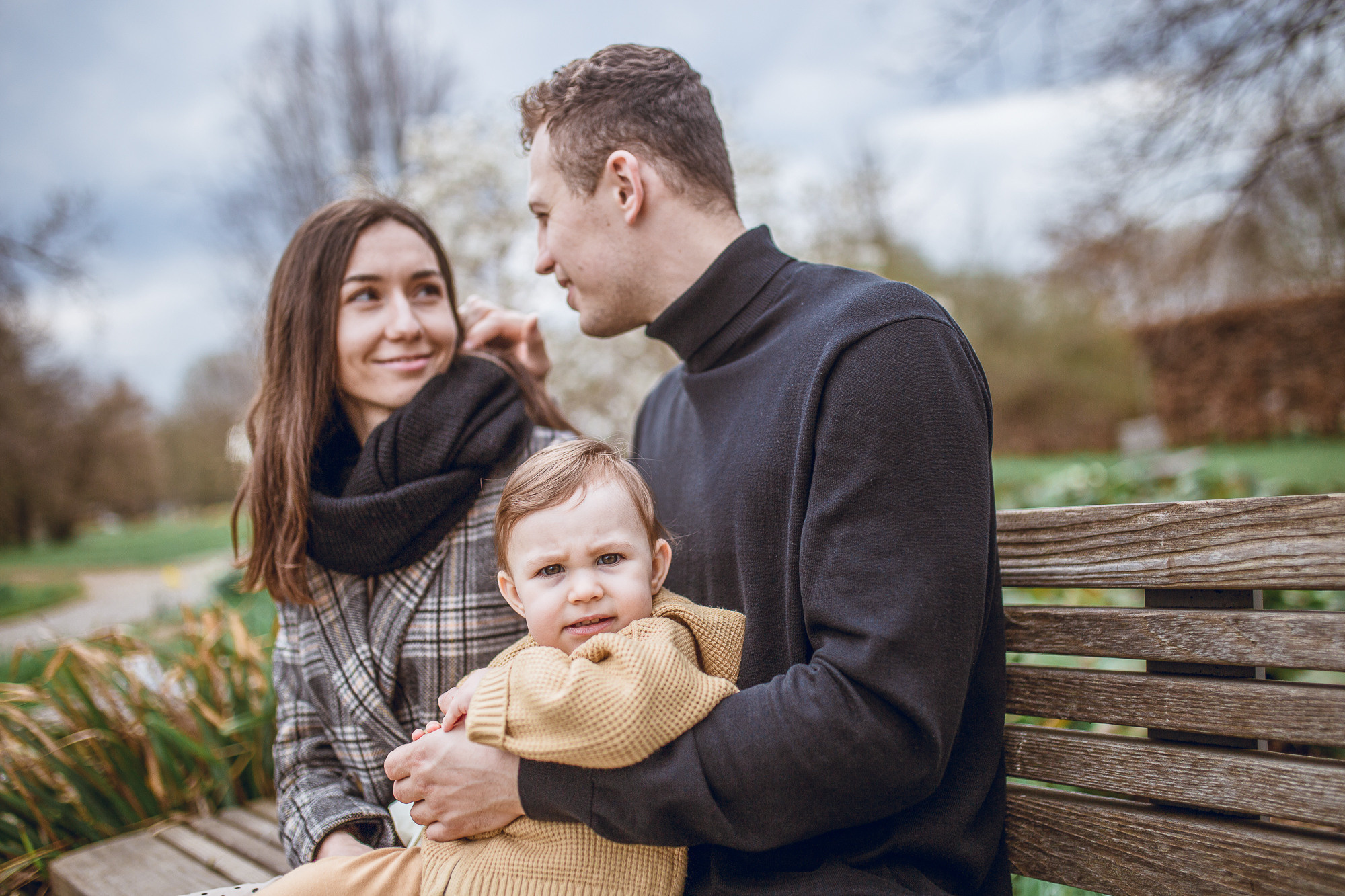 Eltern sitzen auf dem Bank, Baby auf den Arm