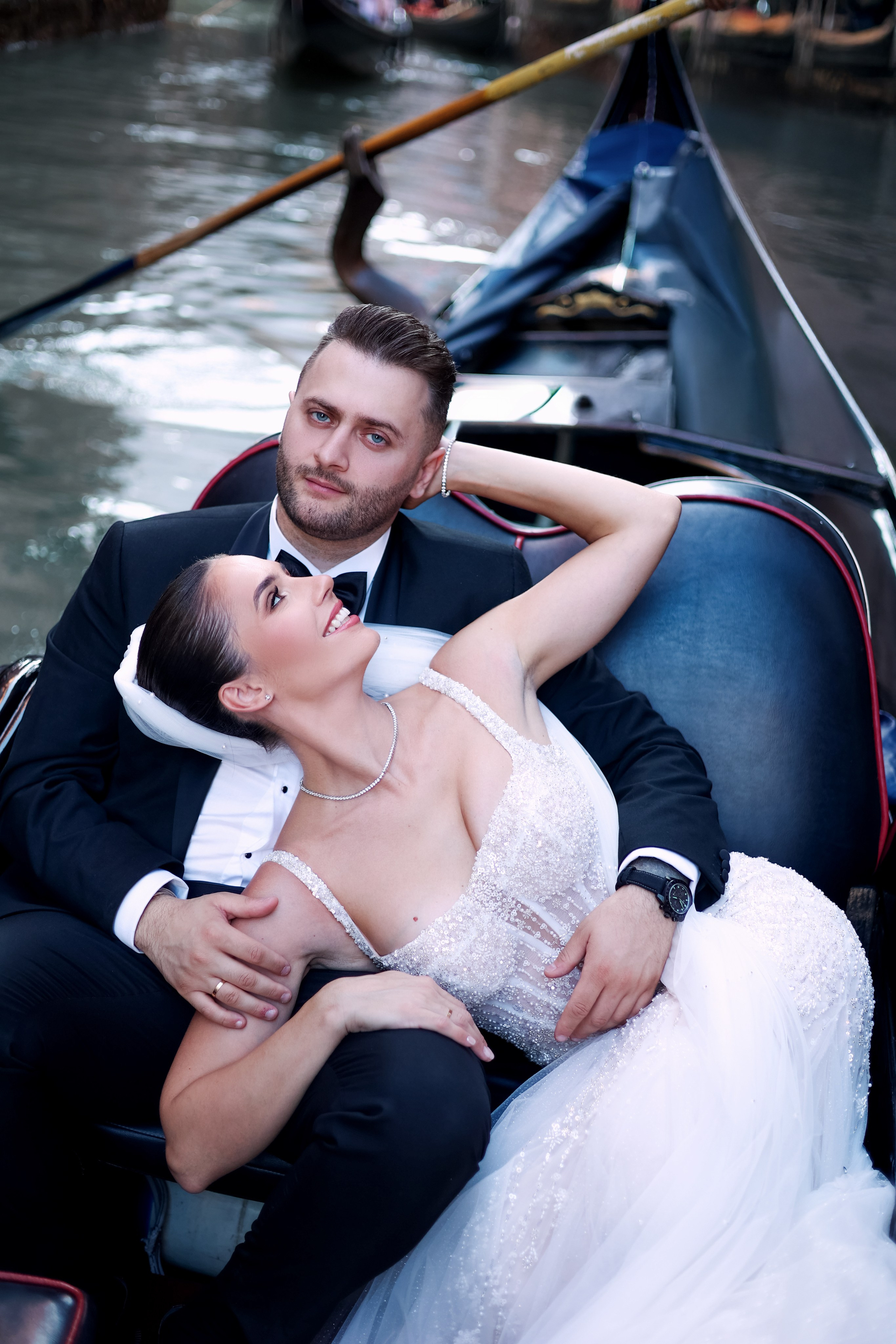 Romantic portrait of a bride and groom by a gondola docked along the Venetian canals