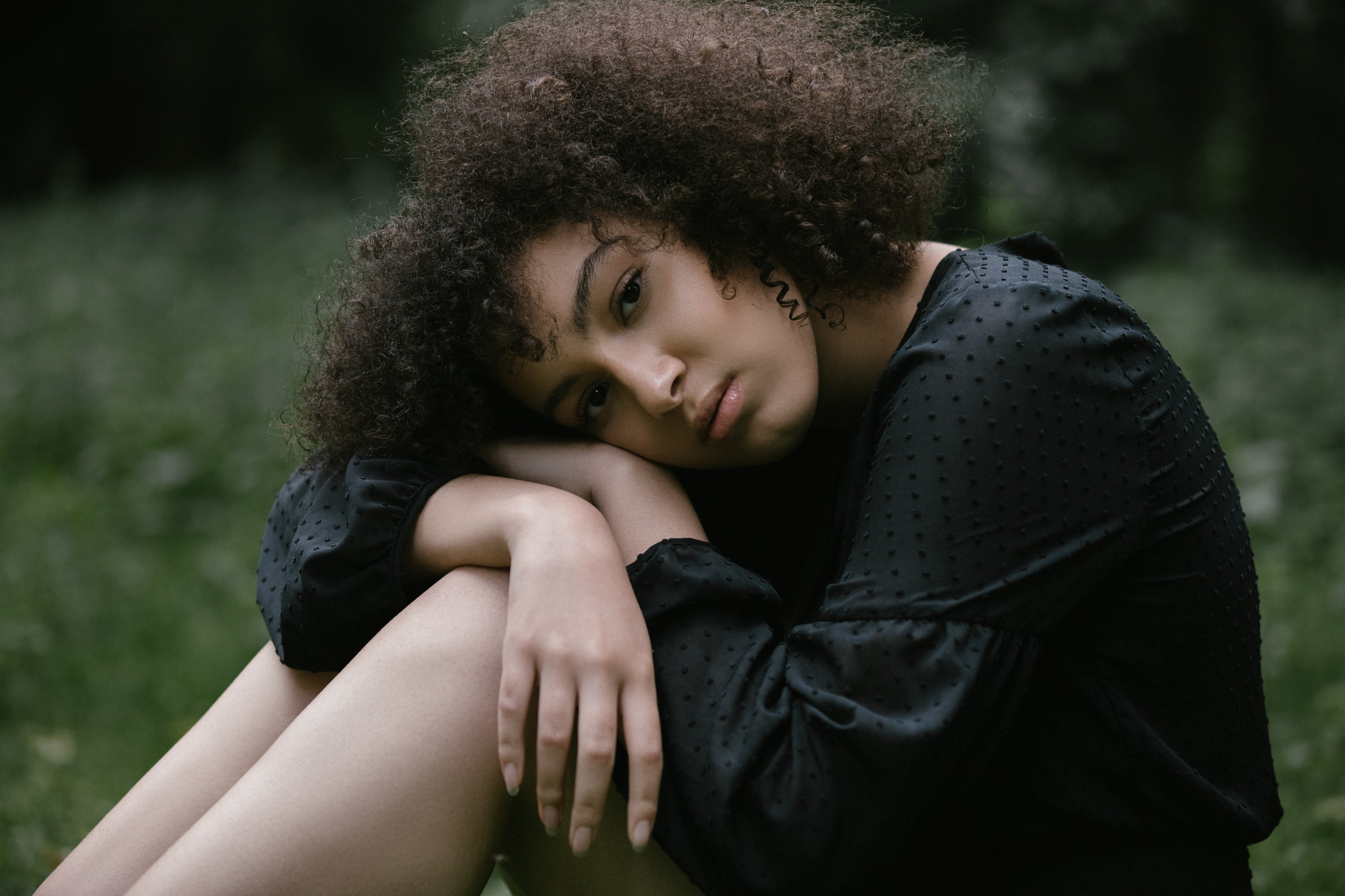 Outdoor portrait, woman resting head on arms, seated pose