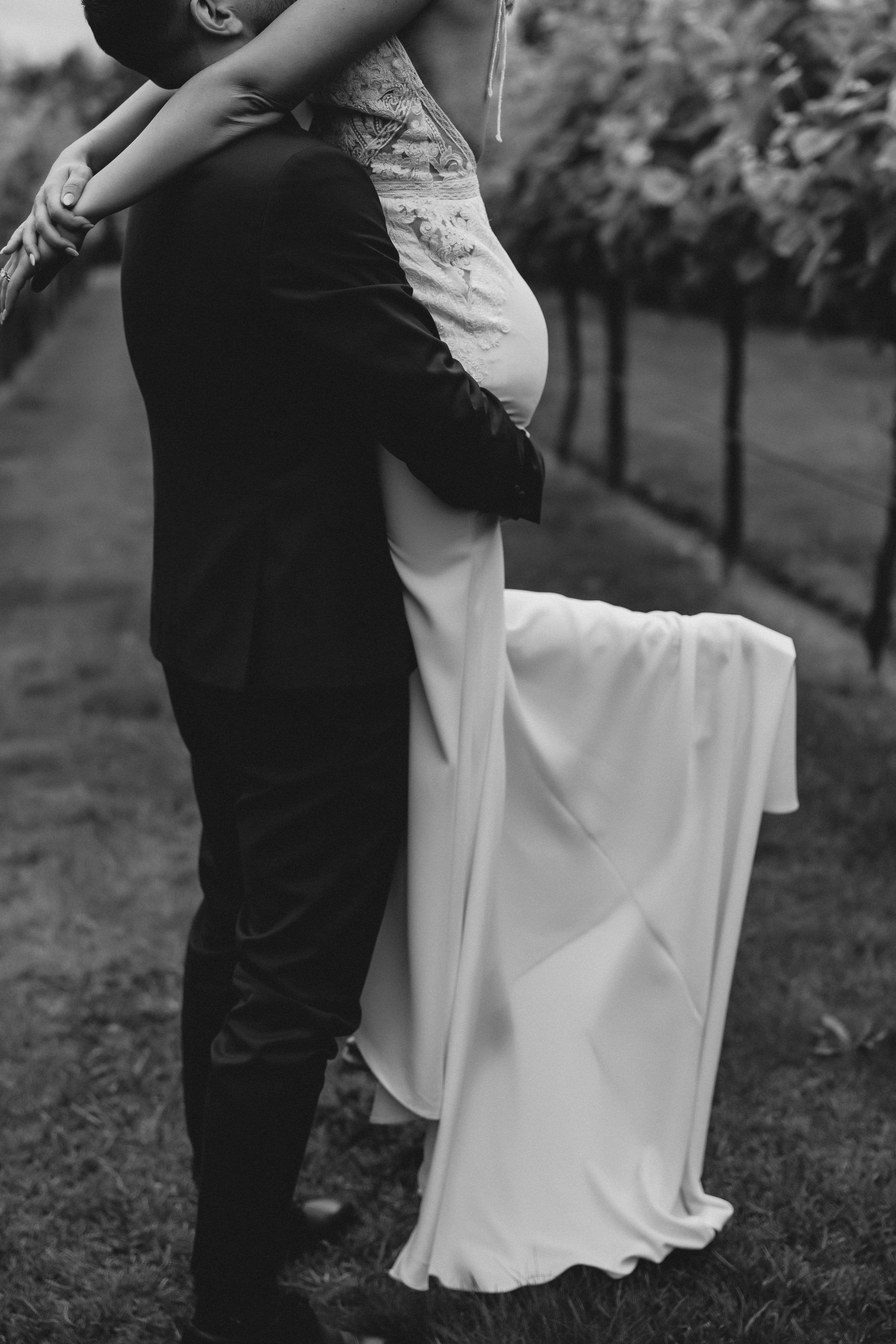 Noivo levanta a noiva num gesto de ternura ao pôr do sol, em ambiente rústico no norte de Portugal.